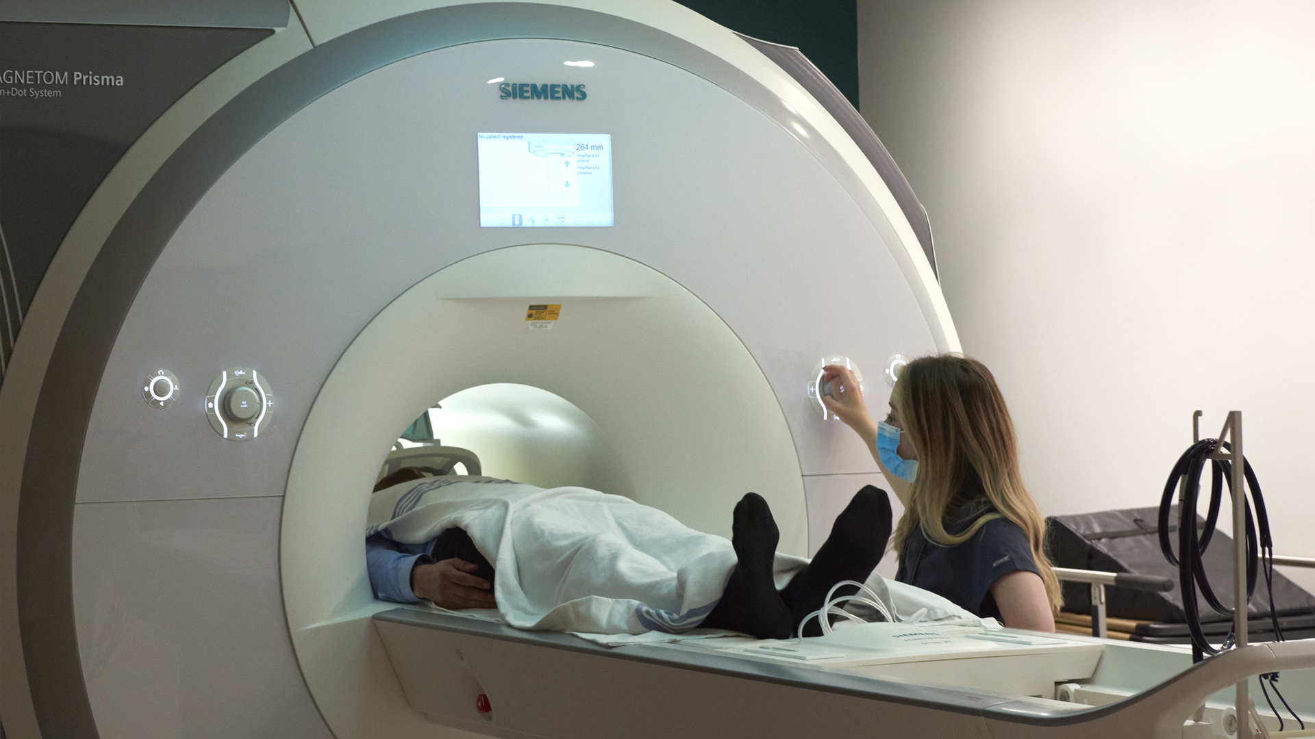 An MRI technologists assists a person entering the MRI scanner