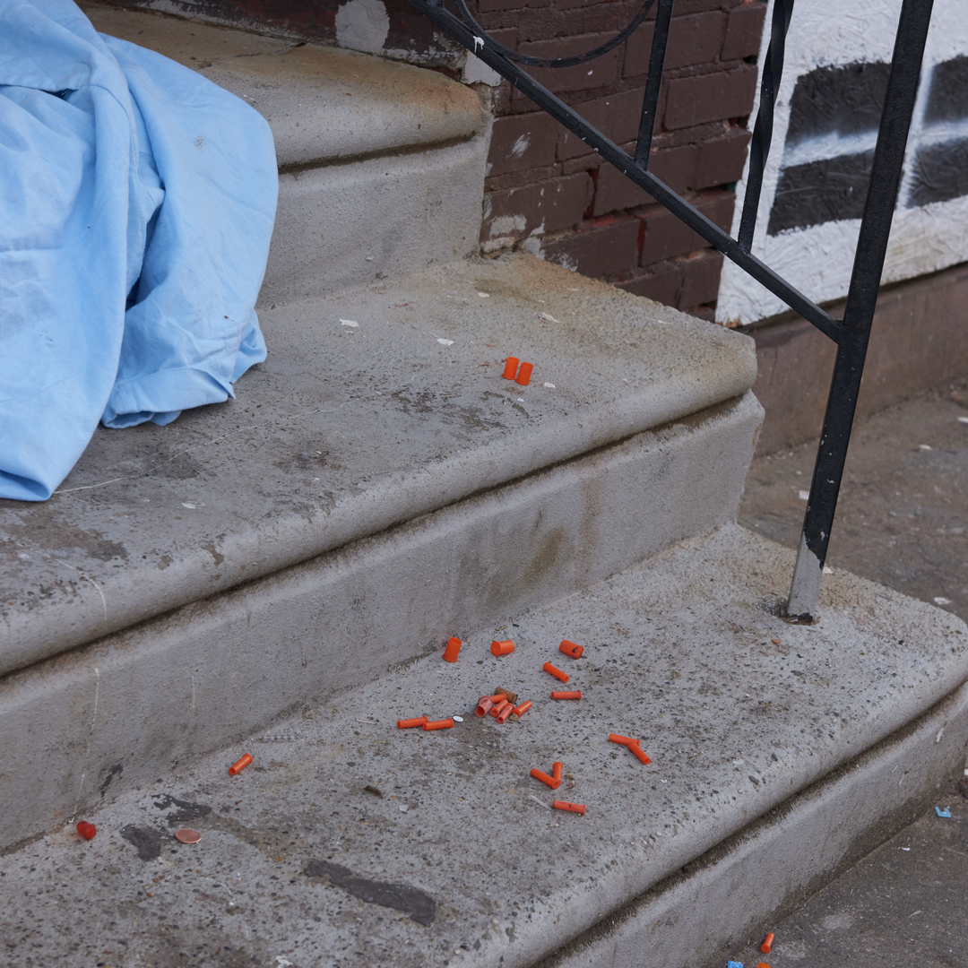 Orange vial caps on concrete steps show signs of illicit drug use