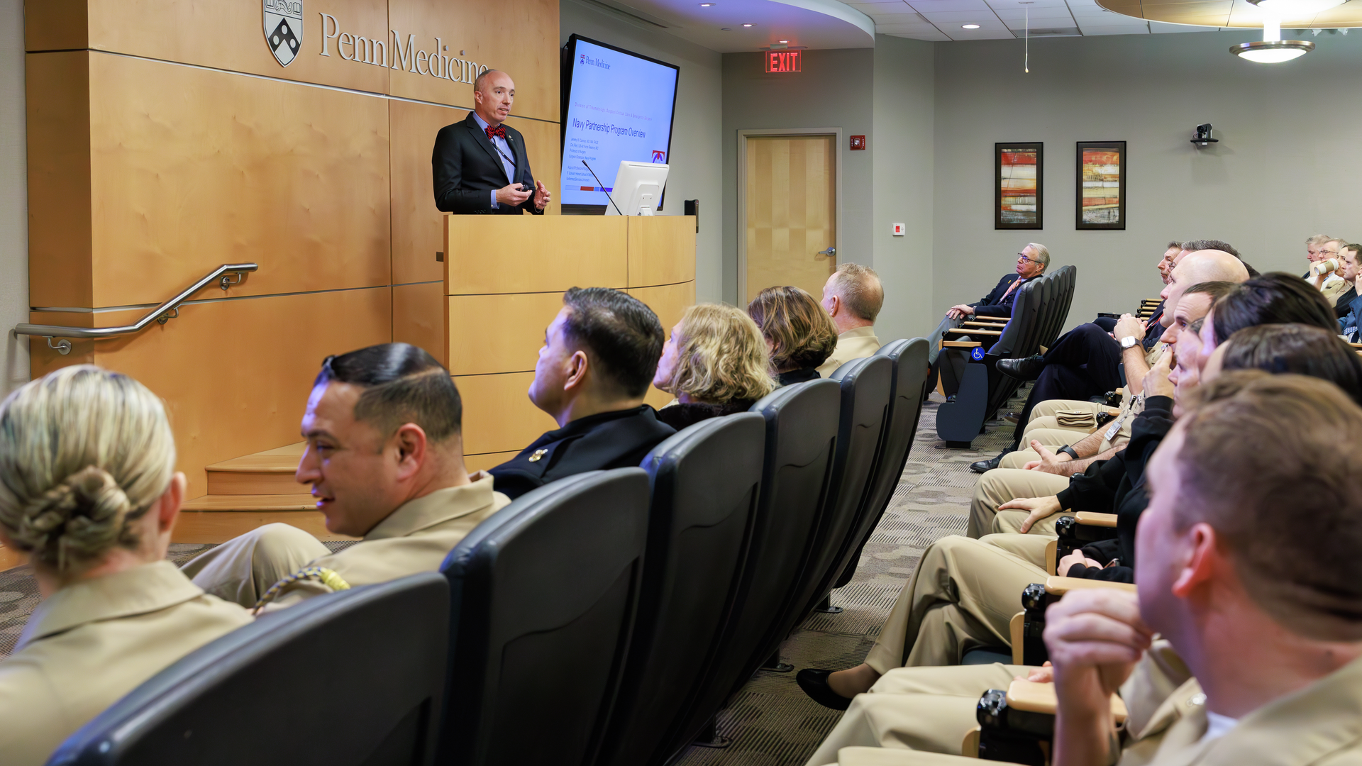 Jeremy Cannon at a podium speaking in front of an audience of Navy personnel
