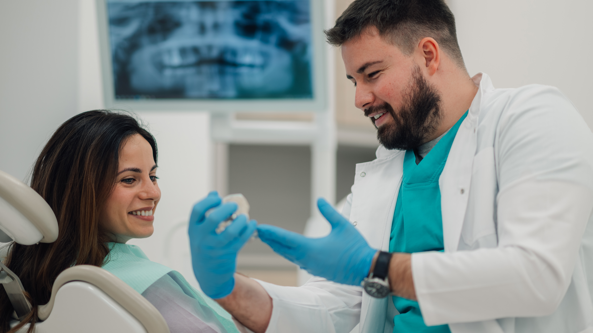 Dentist showing teeth model to patient in modern clinic