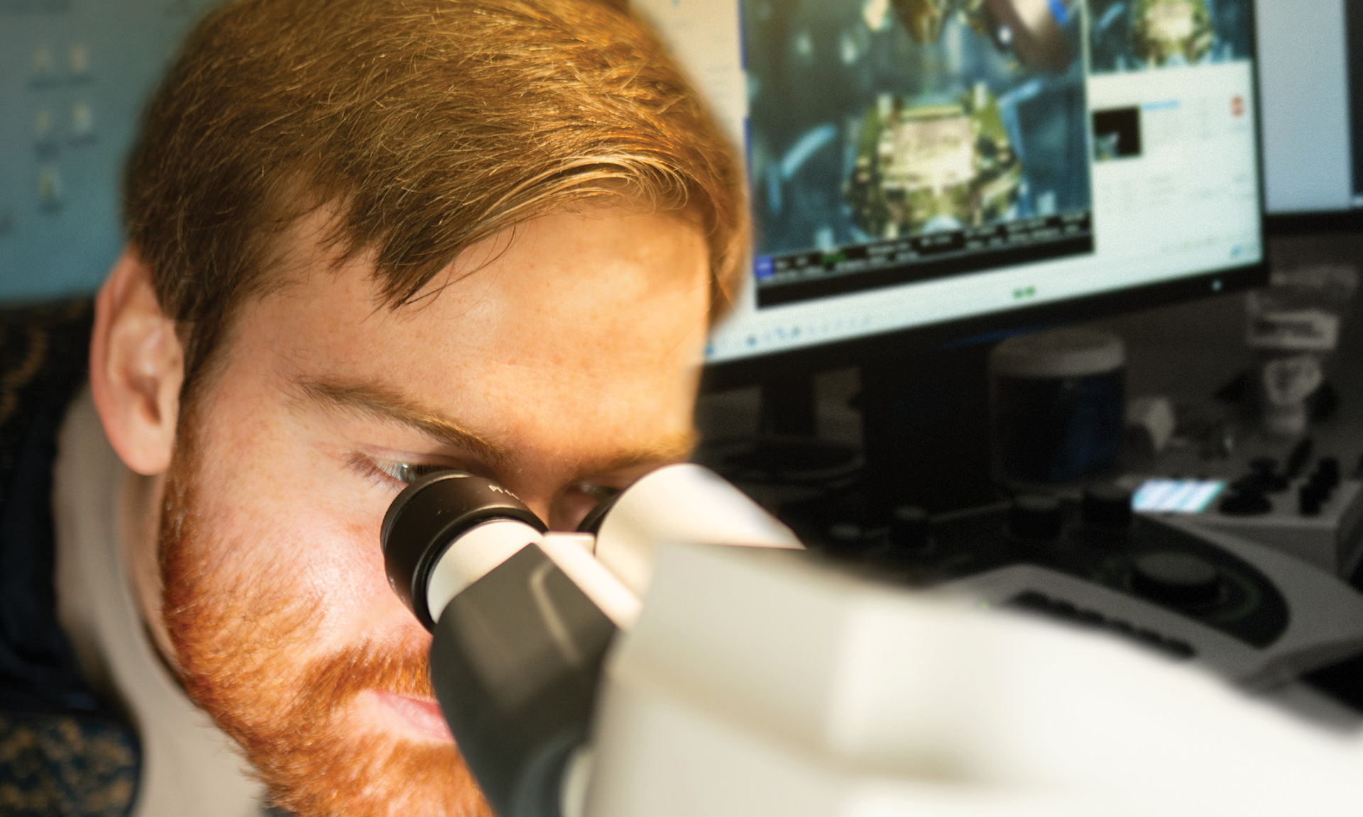 Benjamin Creekmore looks into the eyepiece of a microscope