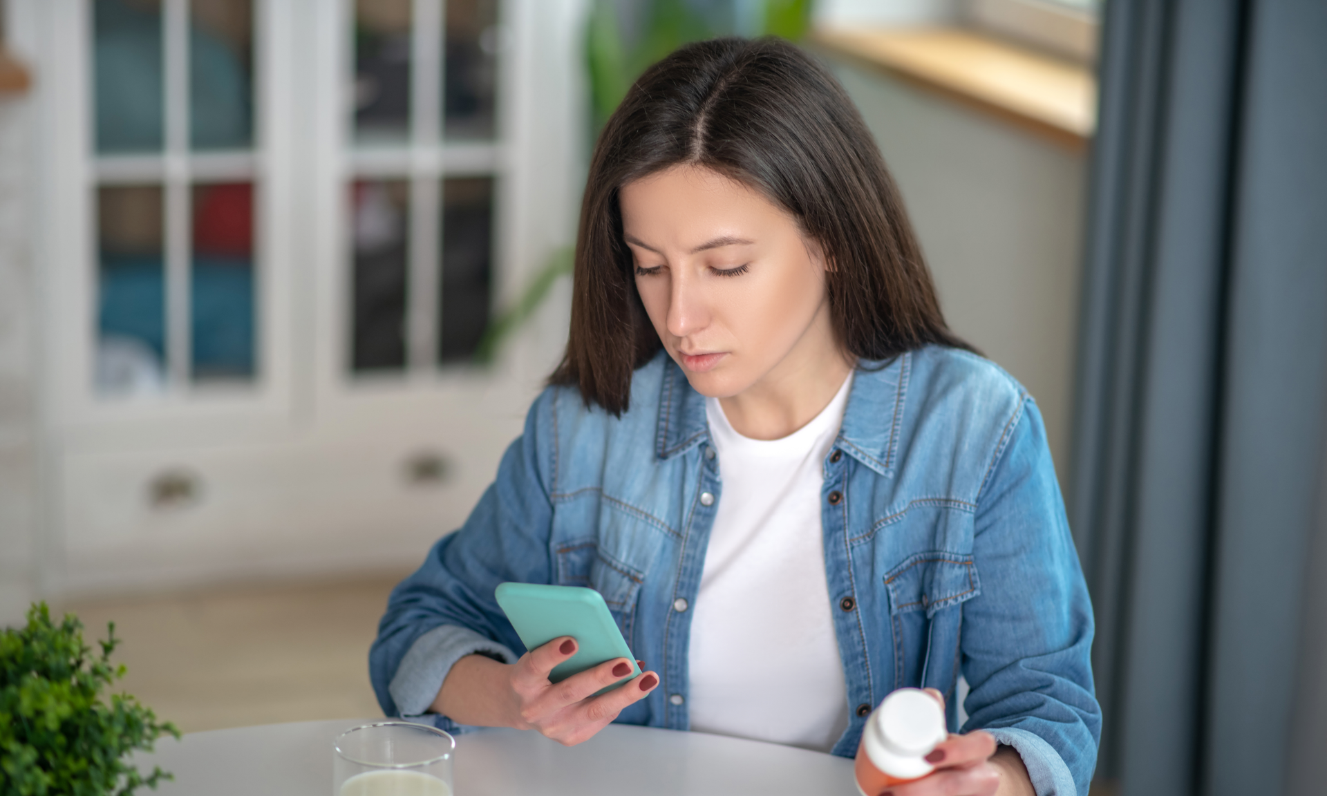 Looking for an instruction. A woman holding a smartphone and pills container