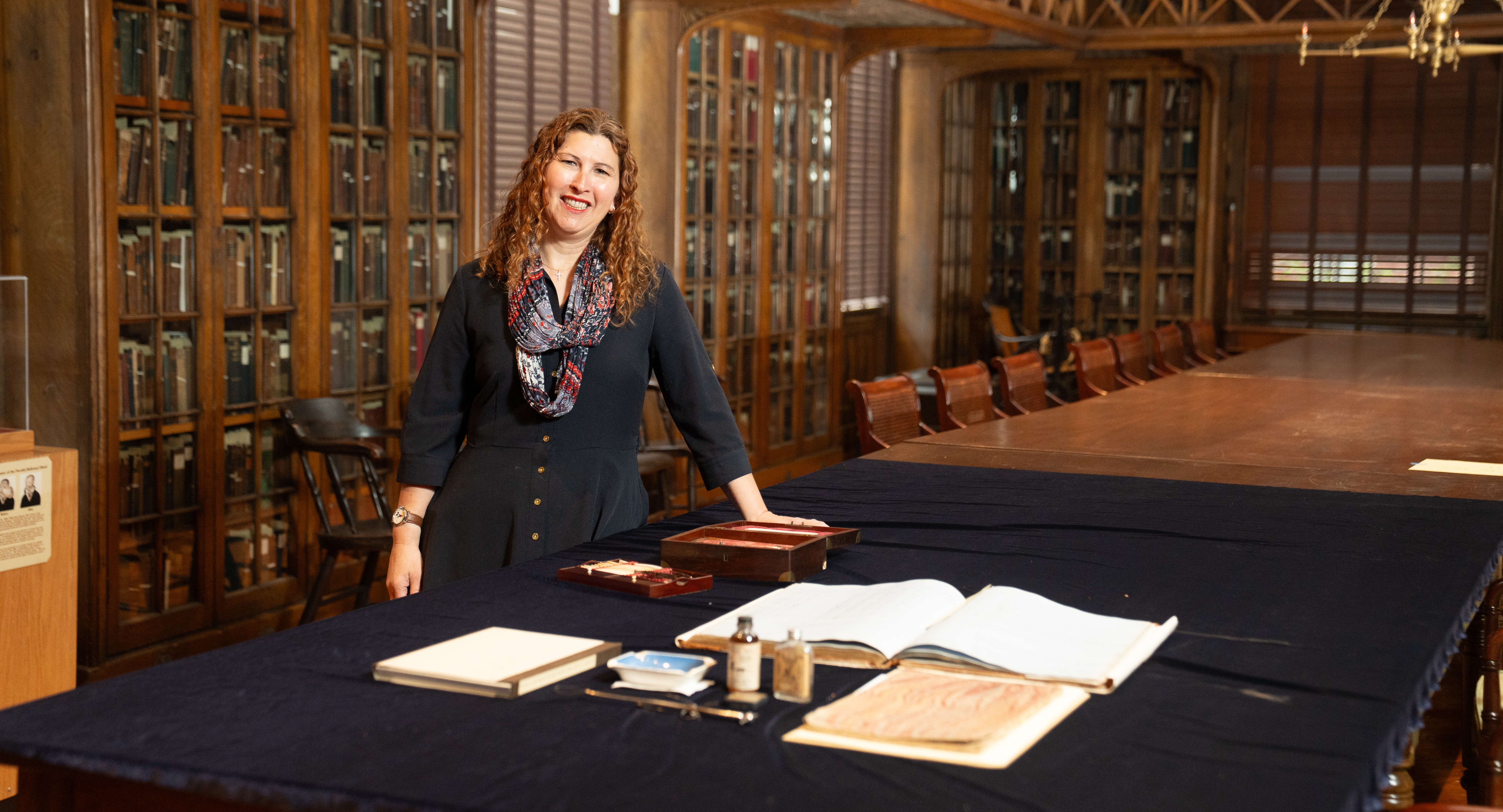 Stacey Peeples in the historic library with an assortment of artifacts on a table