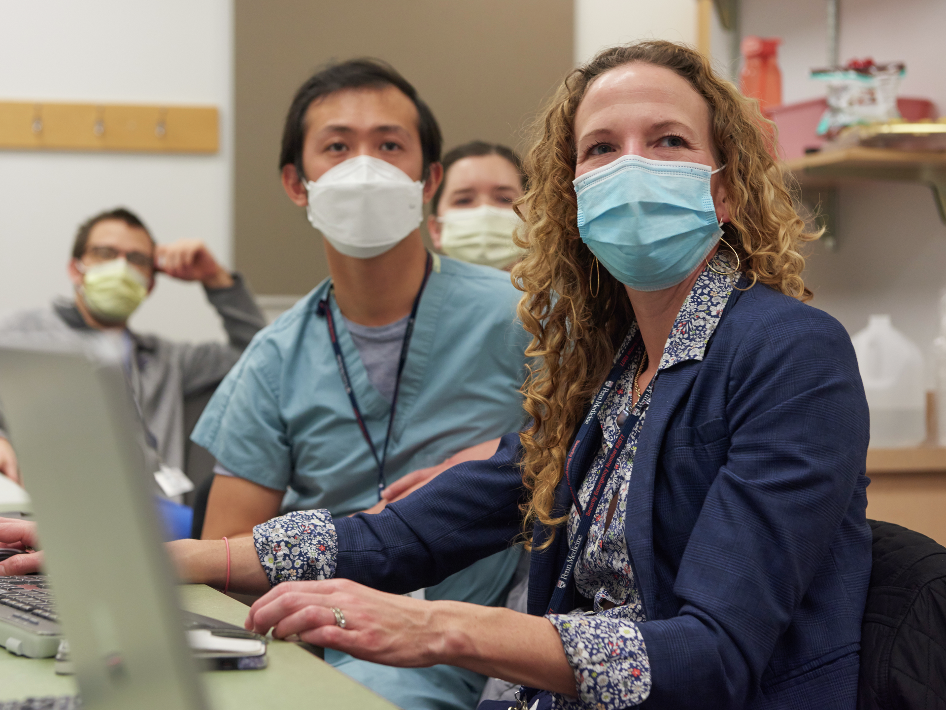 Nova Panebianco, wearing a mask, seated next to a colleague in scrubs
