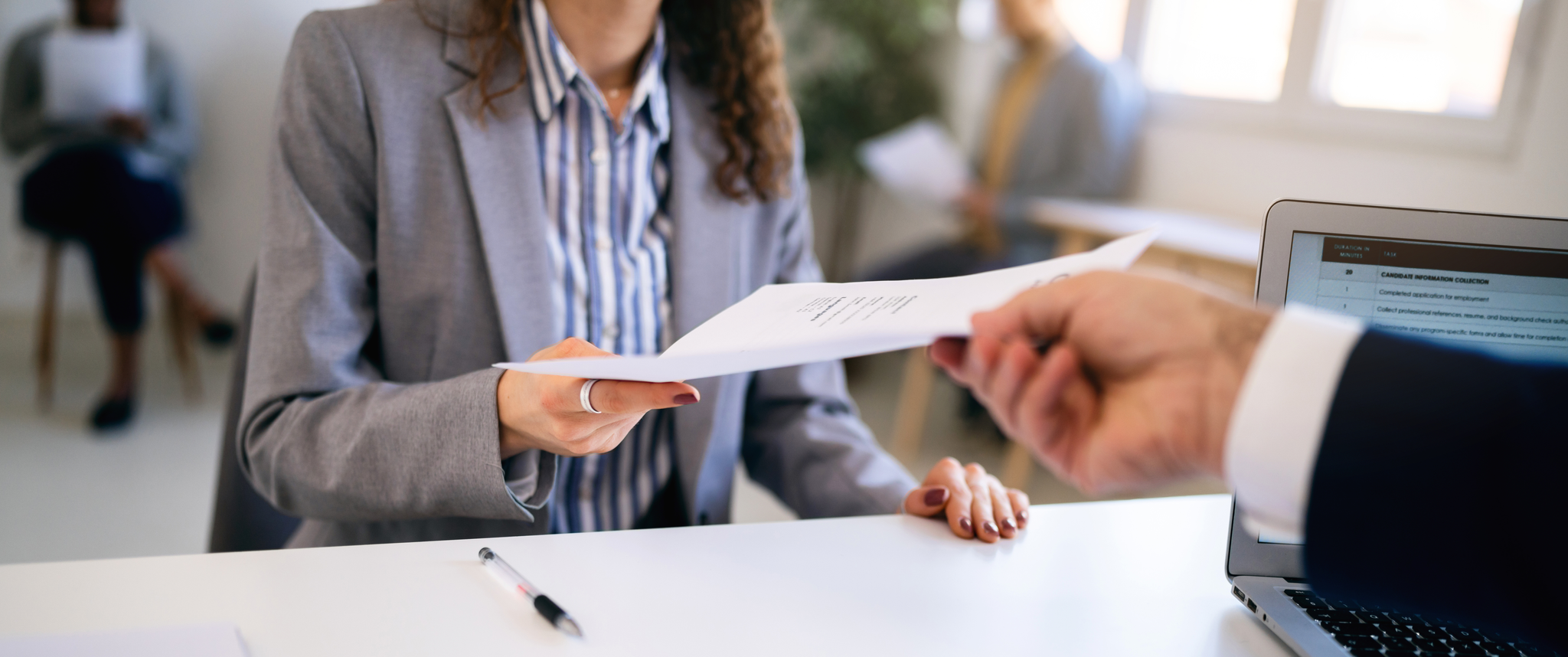 Candidate hands her resume to a recruiter during job interview