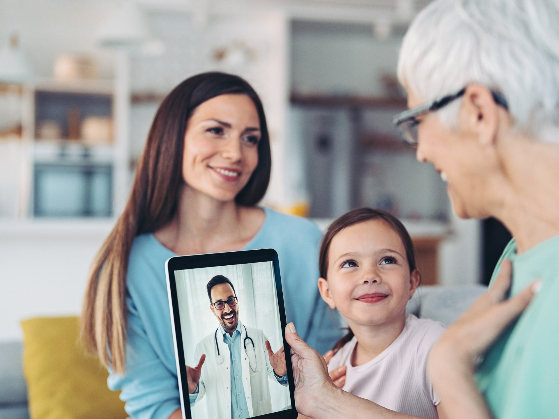 Grandmother, mother and daughter in a telehealth call with a doctor.