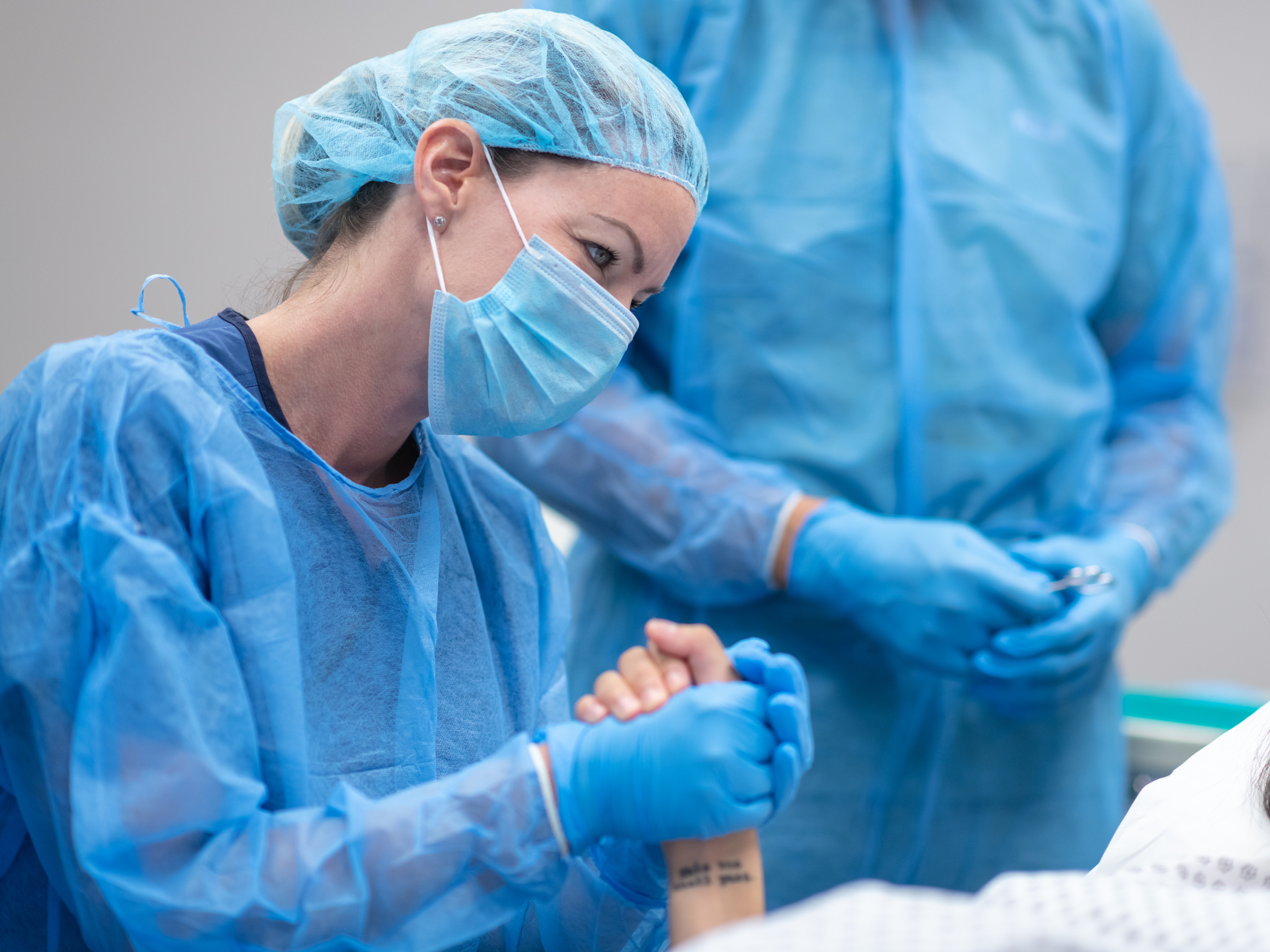 Surgeon holding patient's hand on operating table