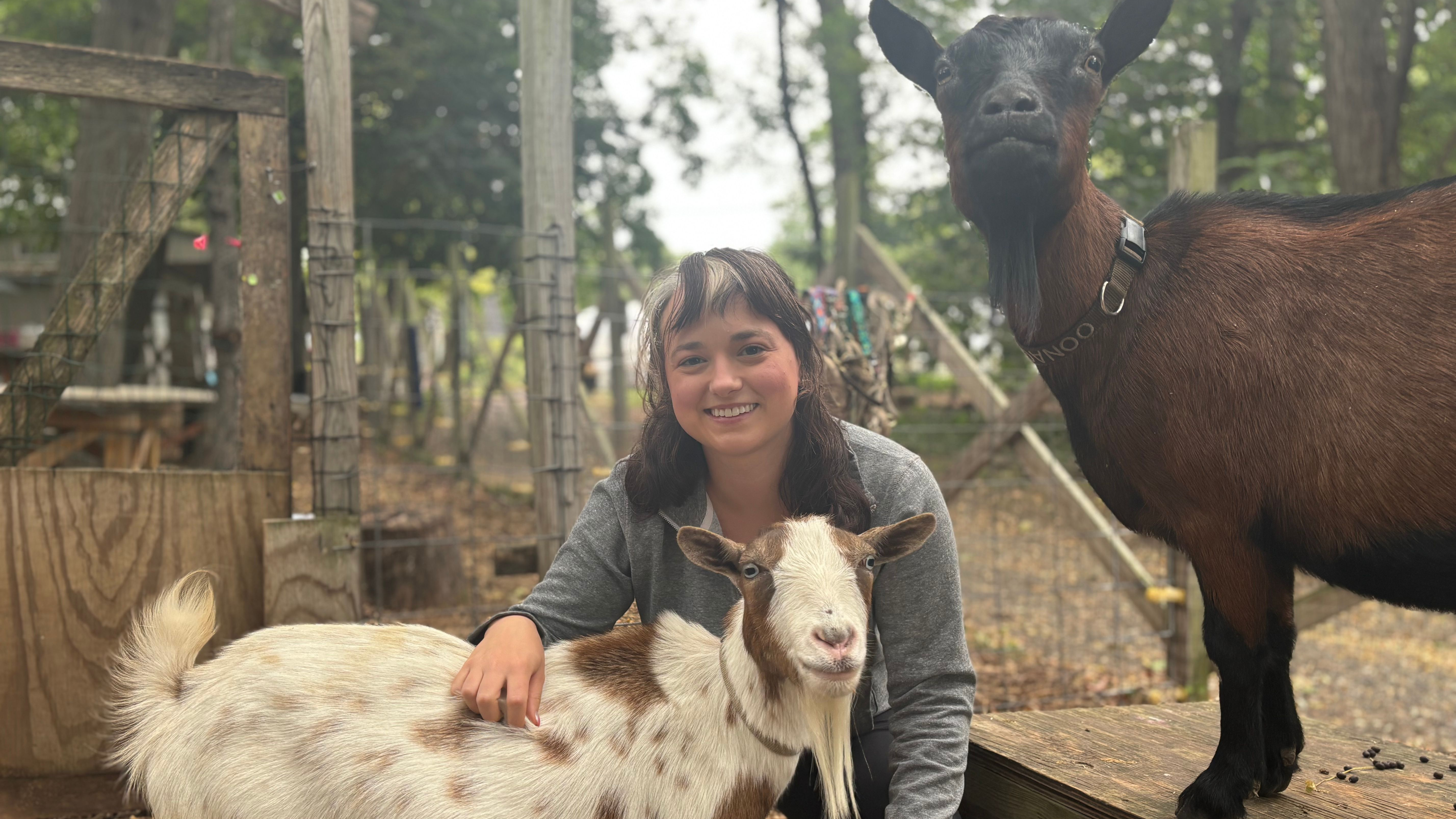 Grace Freund smiling with the two goats on a farm