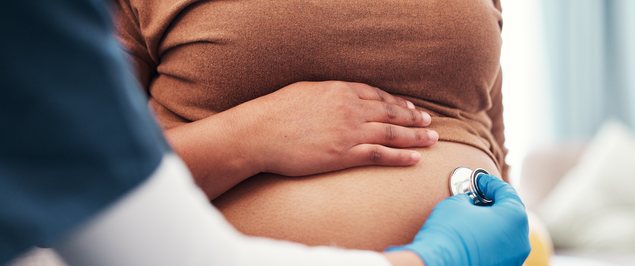 Closeup of pregnant woman's belly with nurse holding stethoscope
