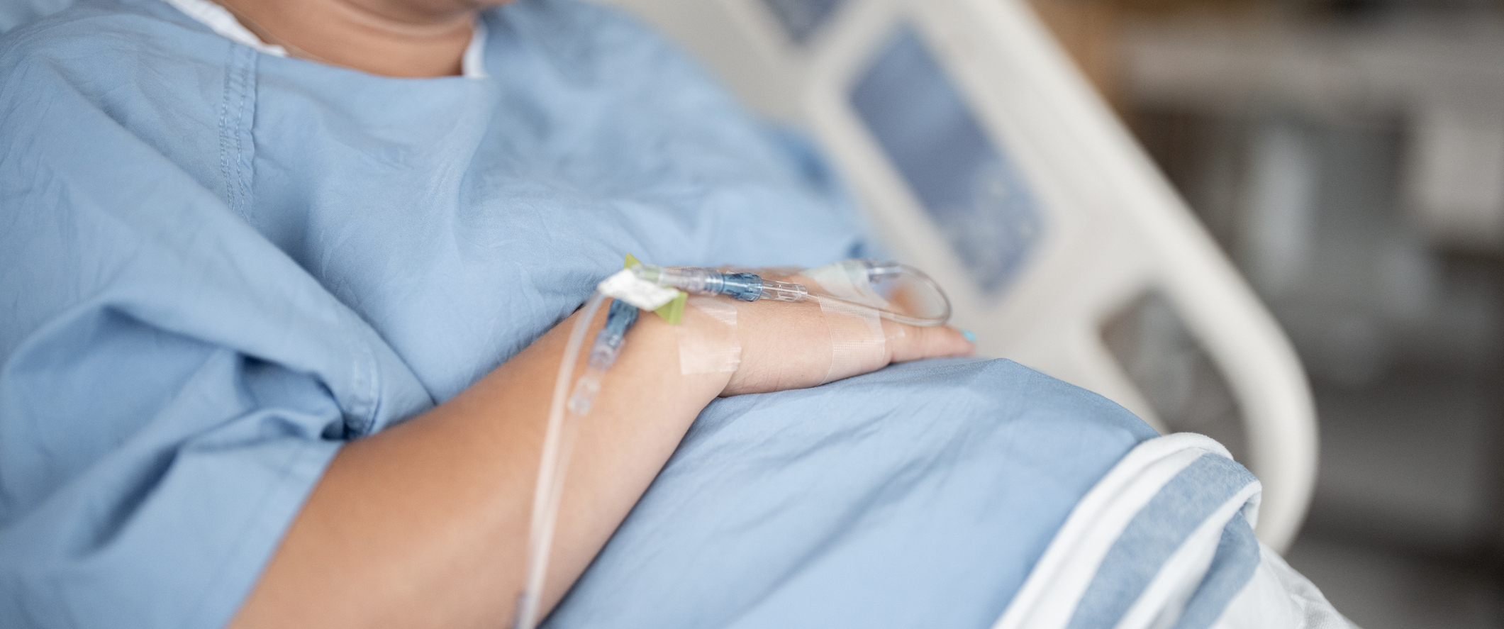 A pregnant patient resting in a hospital bed with an IV line