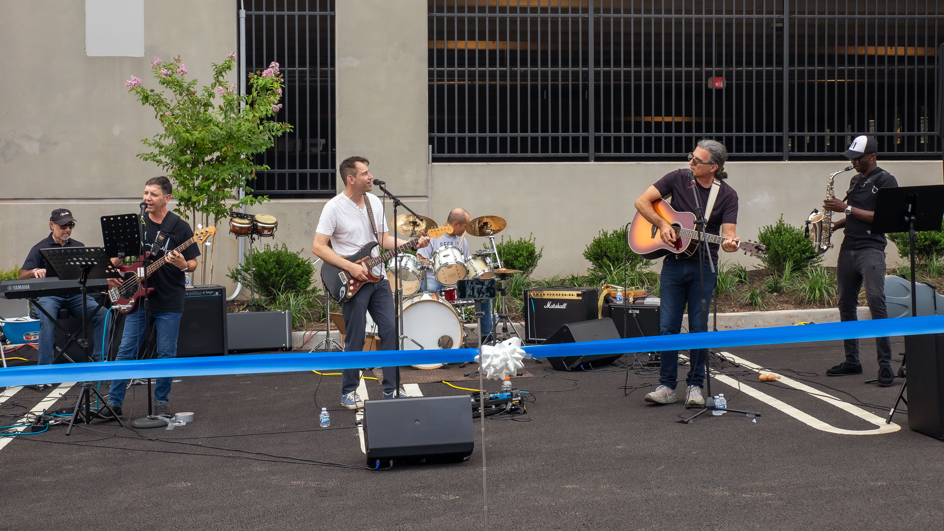 Members of the band Full Code play their instruments and sing outside of a new parking garage