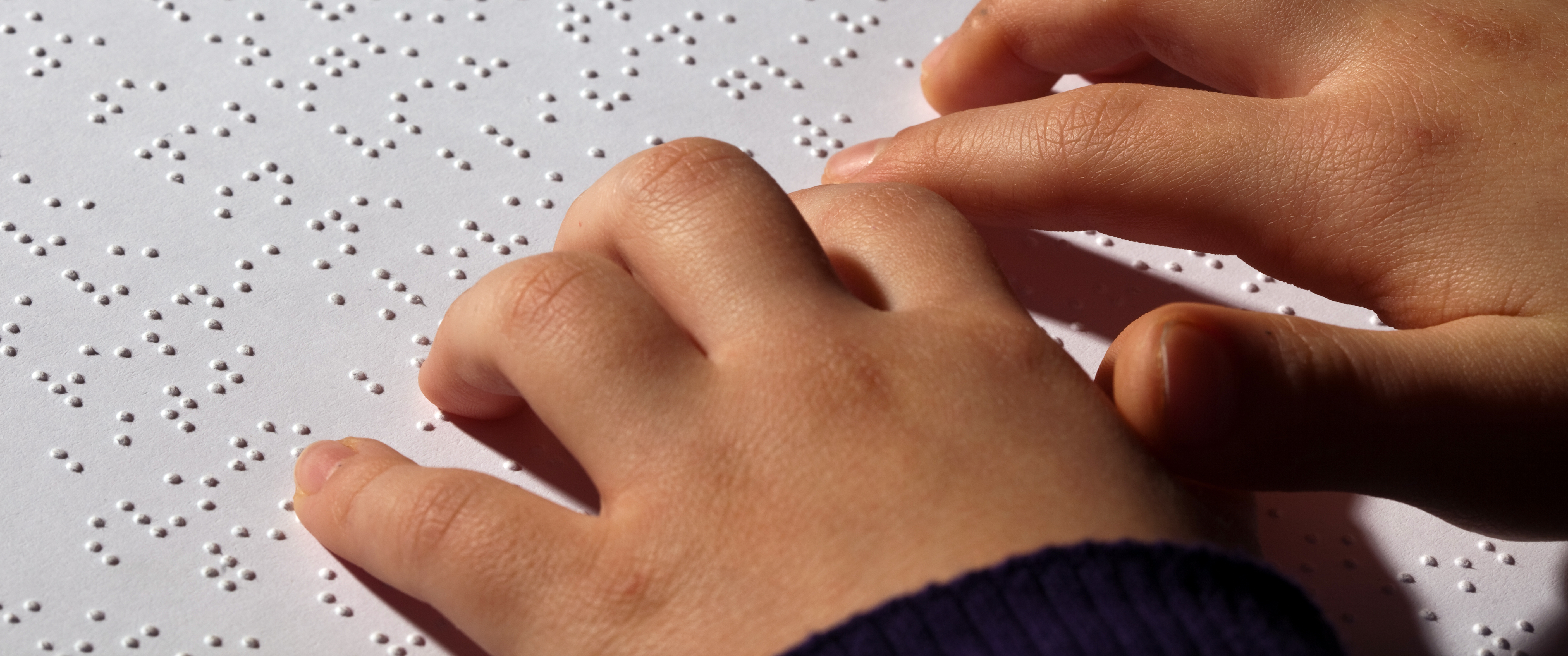 A child's hands reading braille