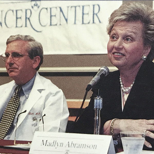Madlyn Abramson and John Glick behind microphones at a table