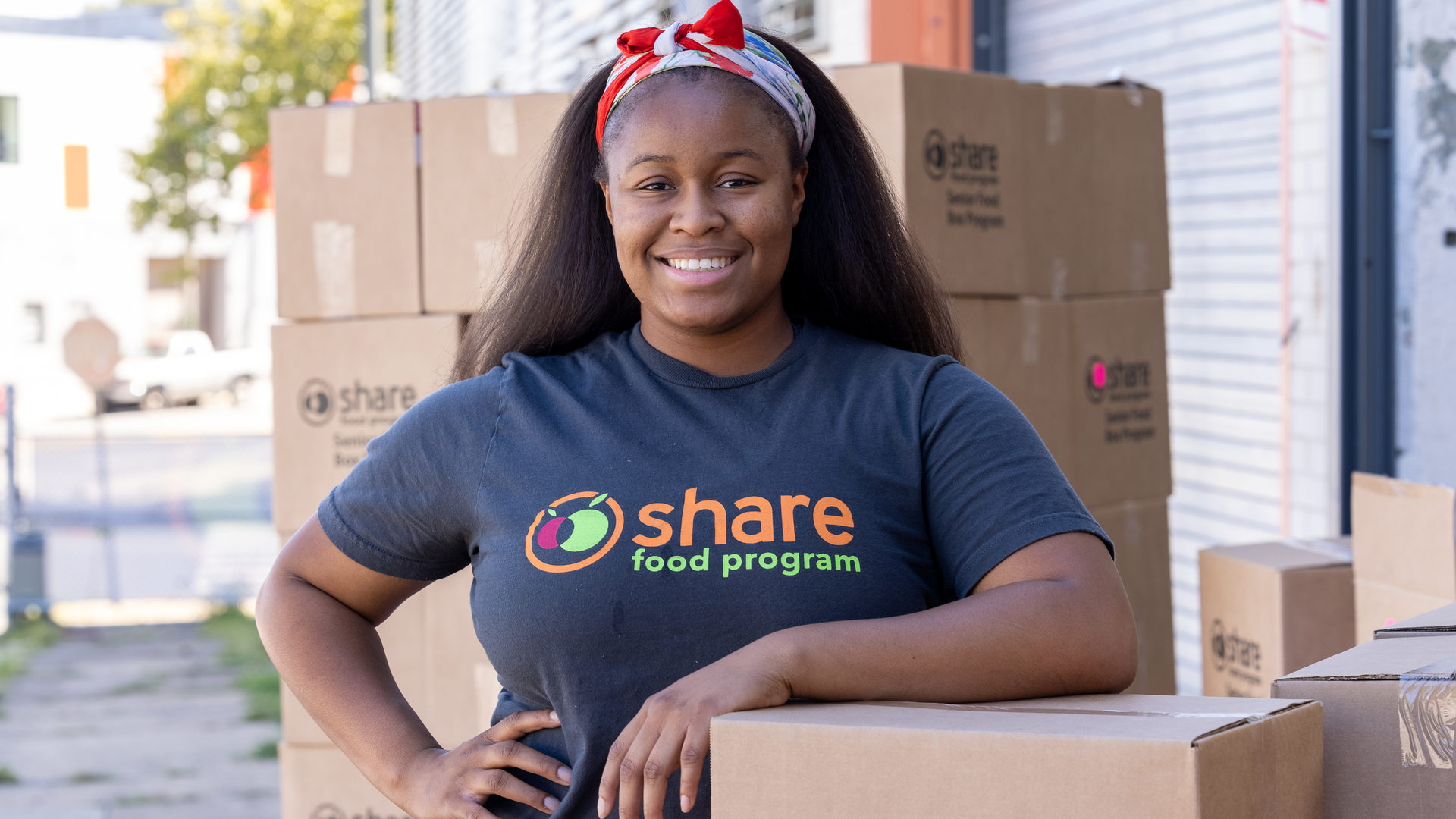 Smiling portrait of Onika Washington-Johnson, a young Black woman wearing a Share Food T-shirt