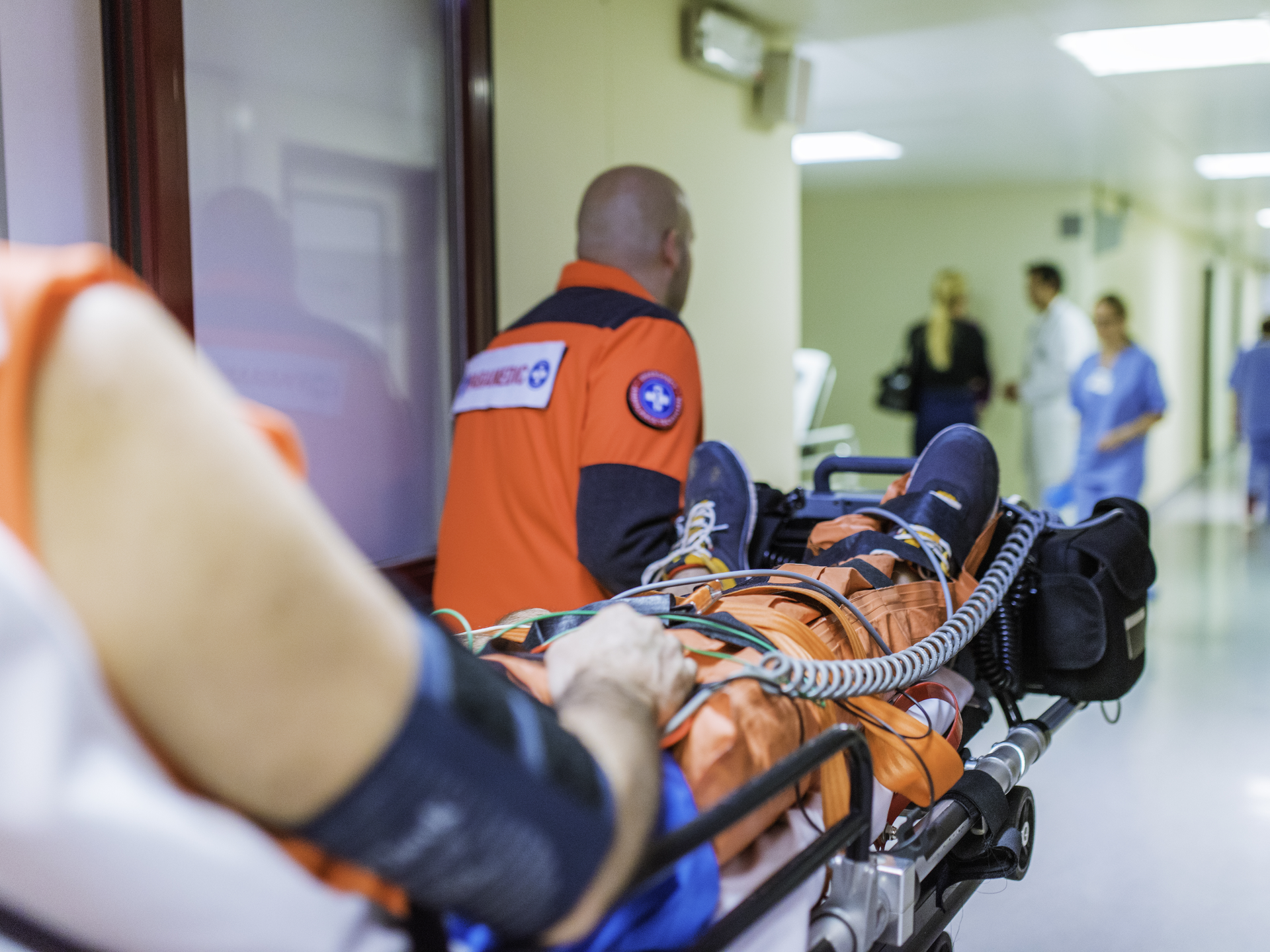 Paramedic pullls hospital gurney with injured patient