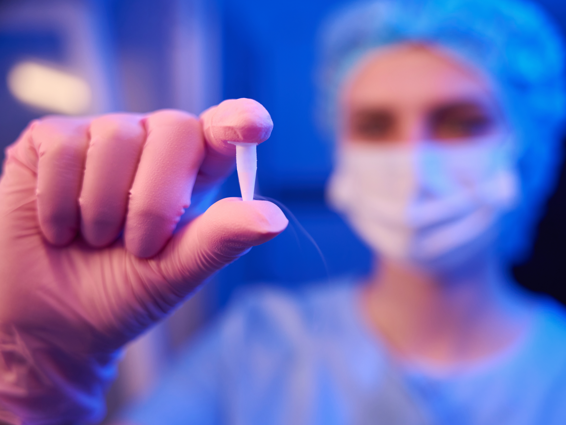 Closeup of scientist hand in sterile glove holding sealed cryogenic vial with frozen human embryos