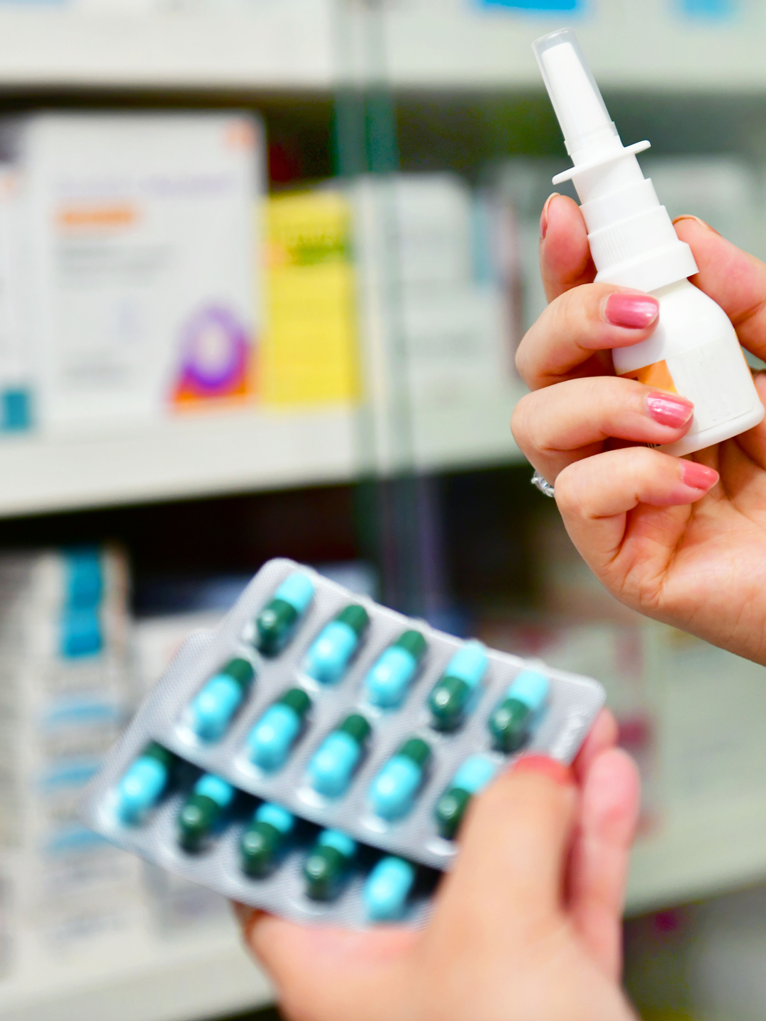 A close-up photo of a hand holding allergy medications in a pharmacy aisle.