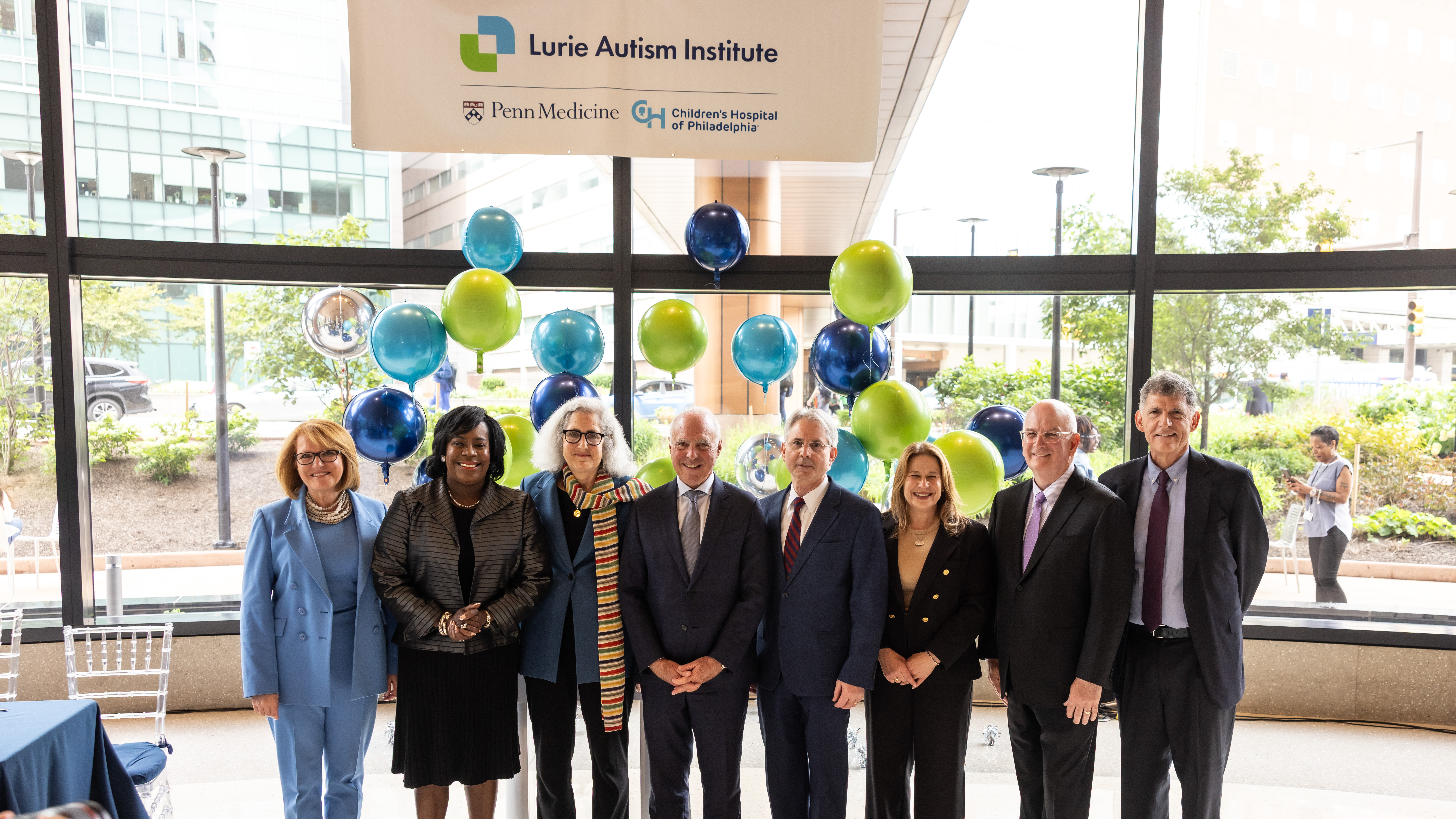 CHOP, Penn Medicine, the Lurie Family, City of Philadelphia, and Commonwealth of Pennsylvania leaders below a sign of the Lurie Autism Institute logo