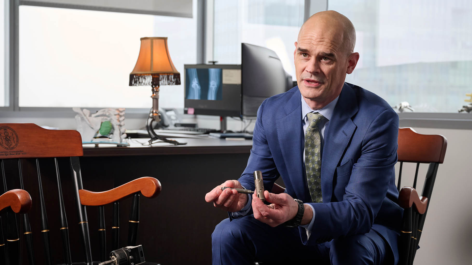 Benjamin “Kyle” Potter, MD, wearing a suit, holding a piece of orthopaedics technology 