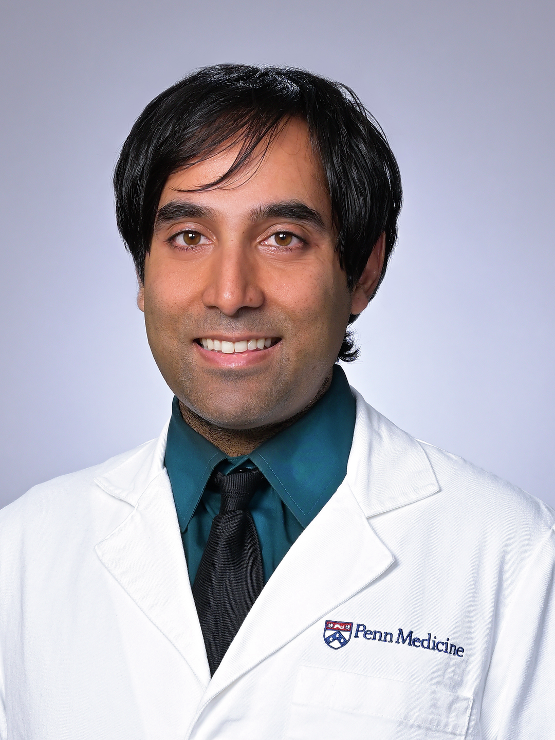Headshot of Clinton Rebello, MD, in a white coat