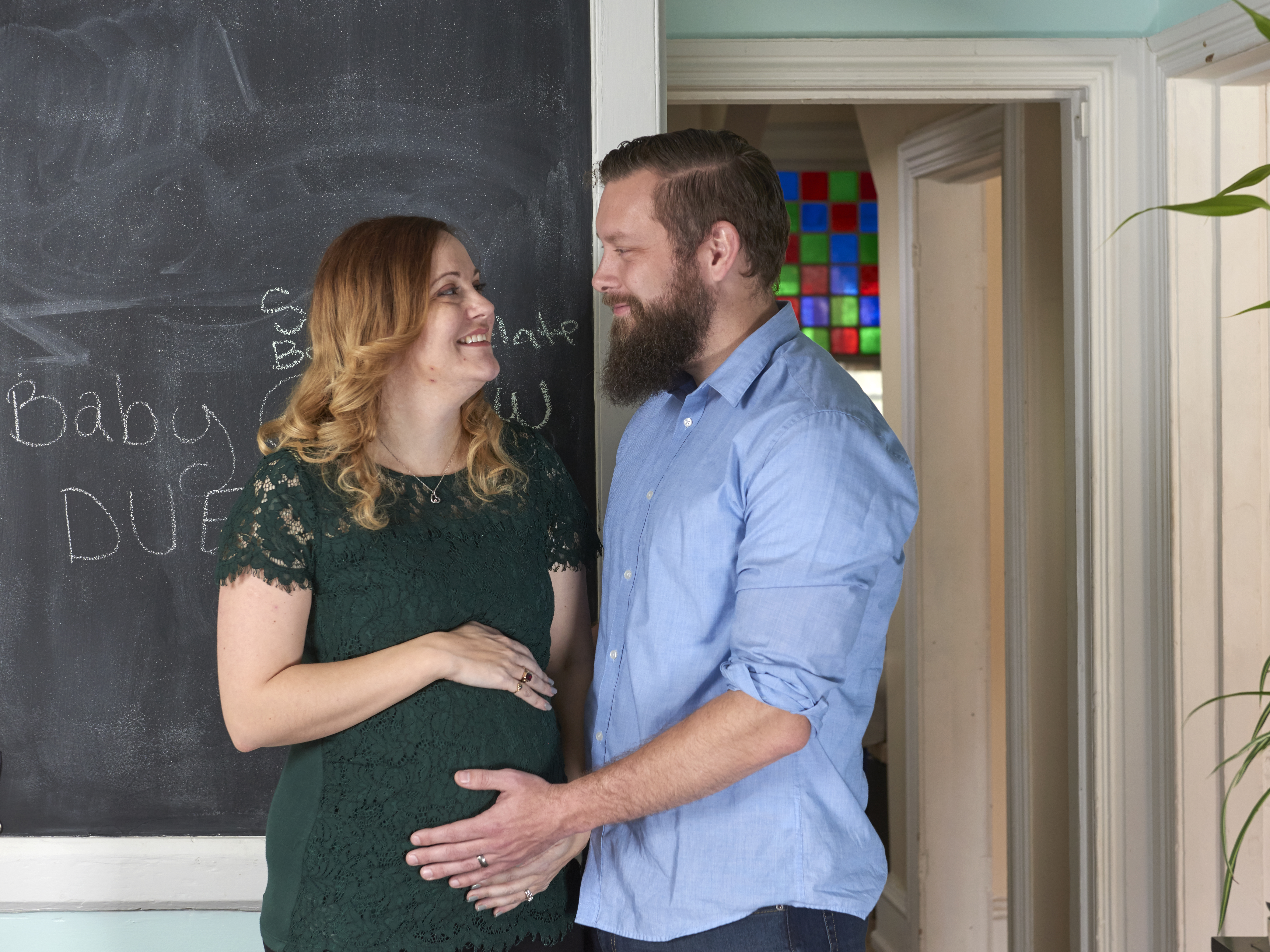 Uterus transplant recipient, Jen Gobrecht, looks lovingly at husband, Drew, as he touches her pregnant belly