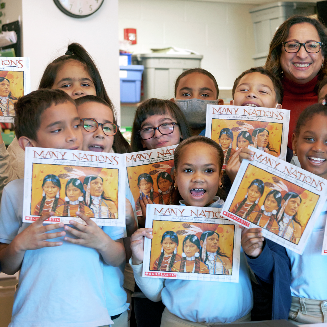 Evelin La Paz stands with a group of elementary students holding up books