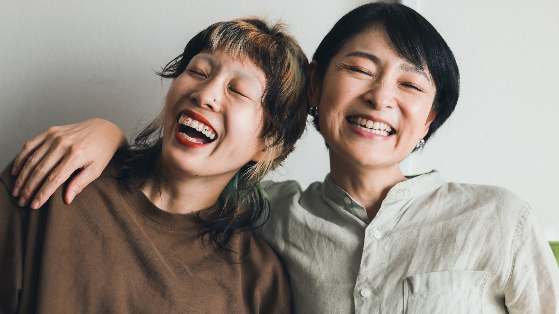Two women laughing and leaning on each other