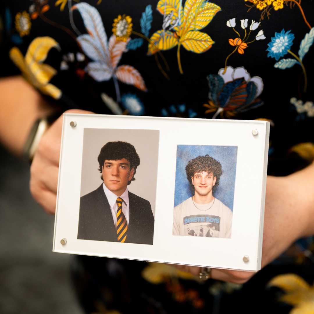 Sara Cohen holding a frame with two photos of her sons—one in college and the other in high school