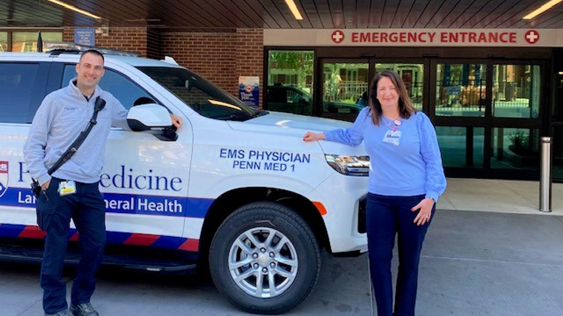 Two Penn Medicine Lancaster General Health employees stand beside the Physician Response Vehicle, parked outside of the Emergency Room entrance.