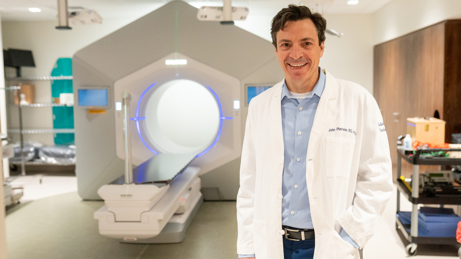 John Plastaras standing in front of a radiation therapy device