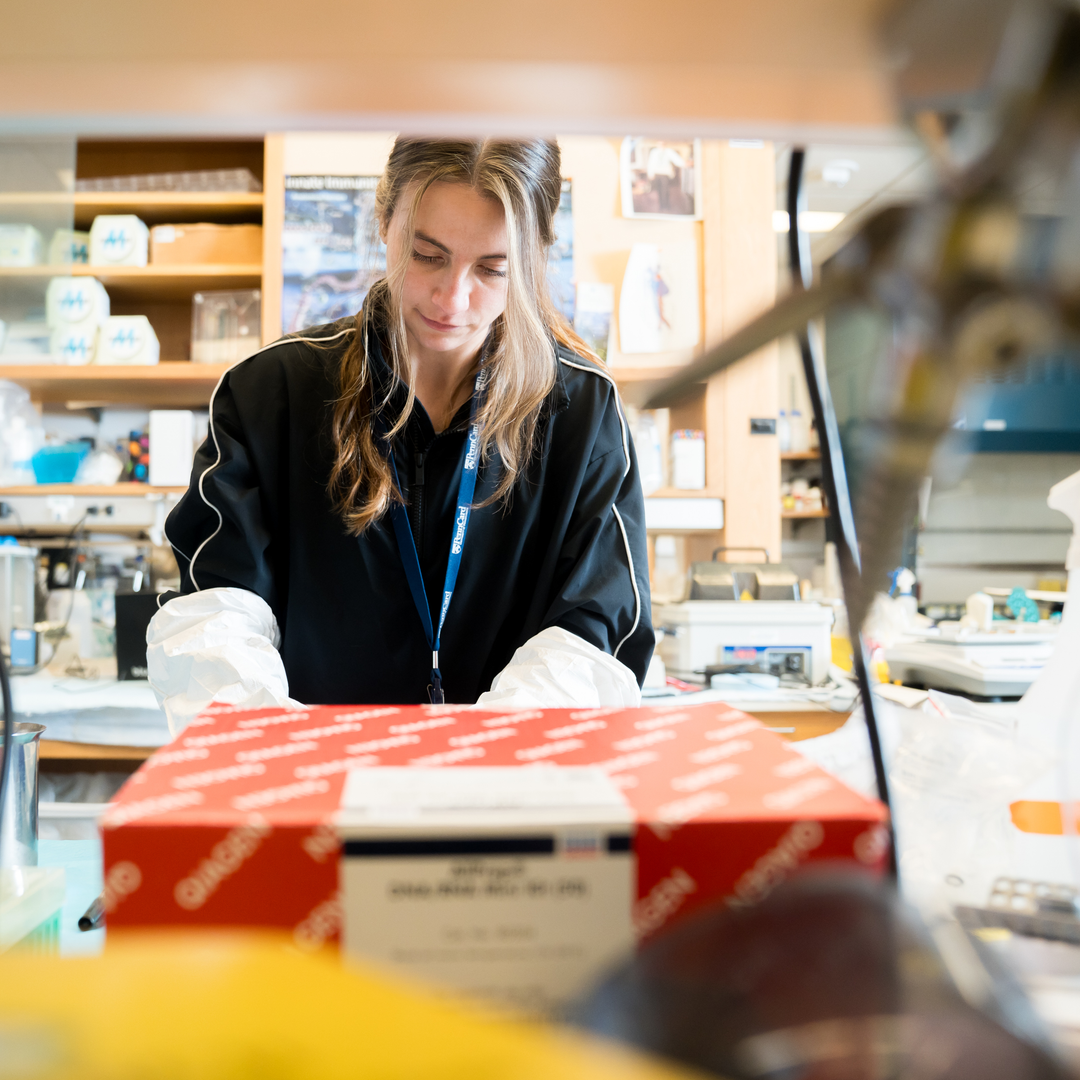 Coral Kasden looks down while working at a lab bench with another scientist