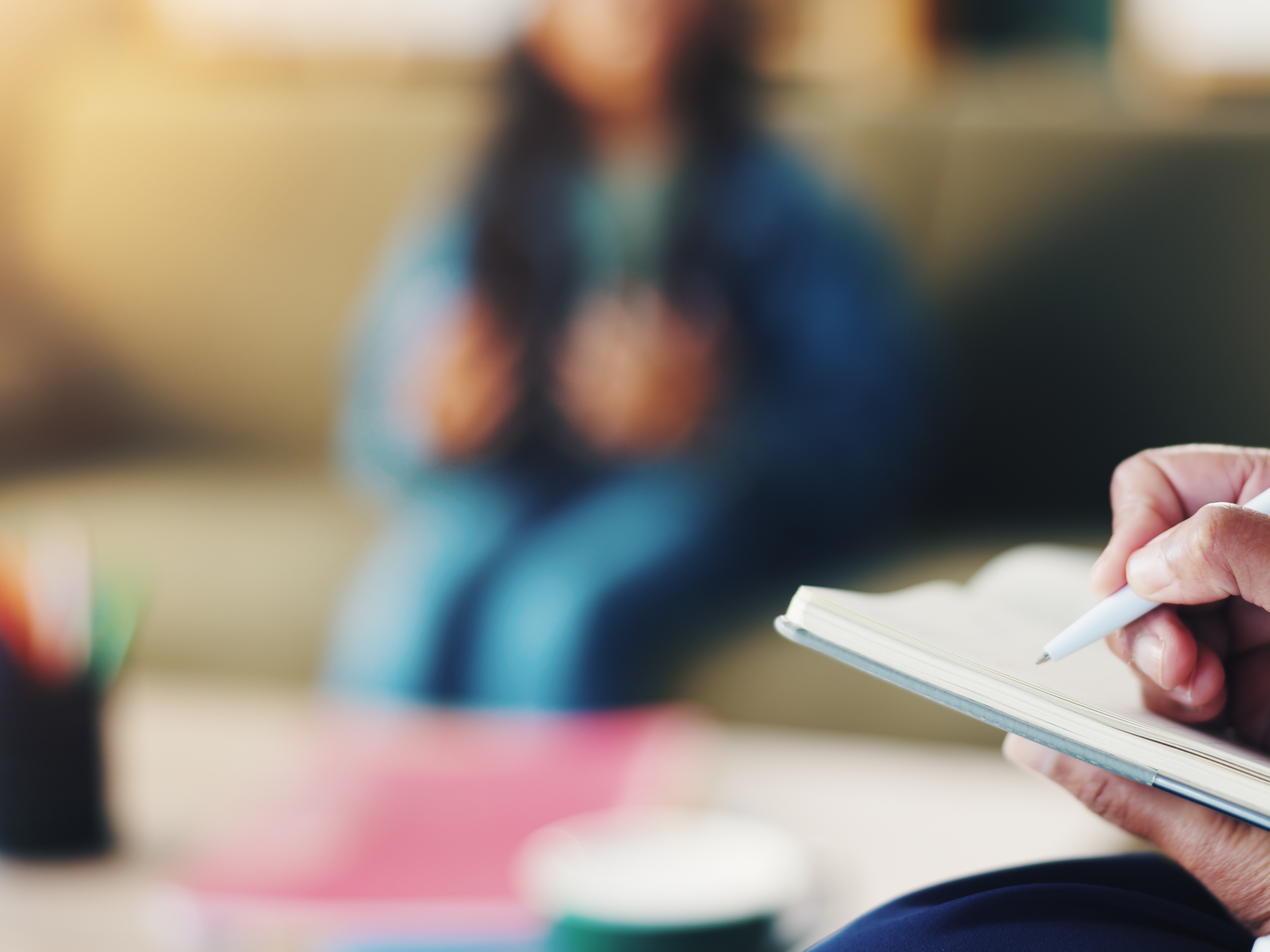 A therapist writes notes while their patient talks