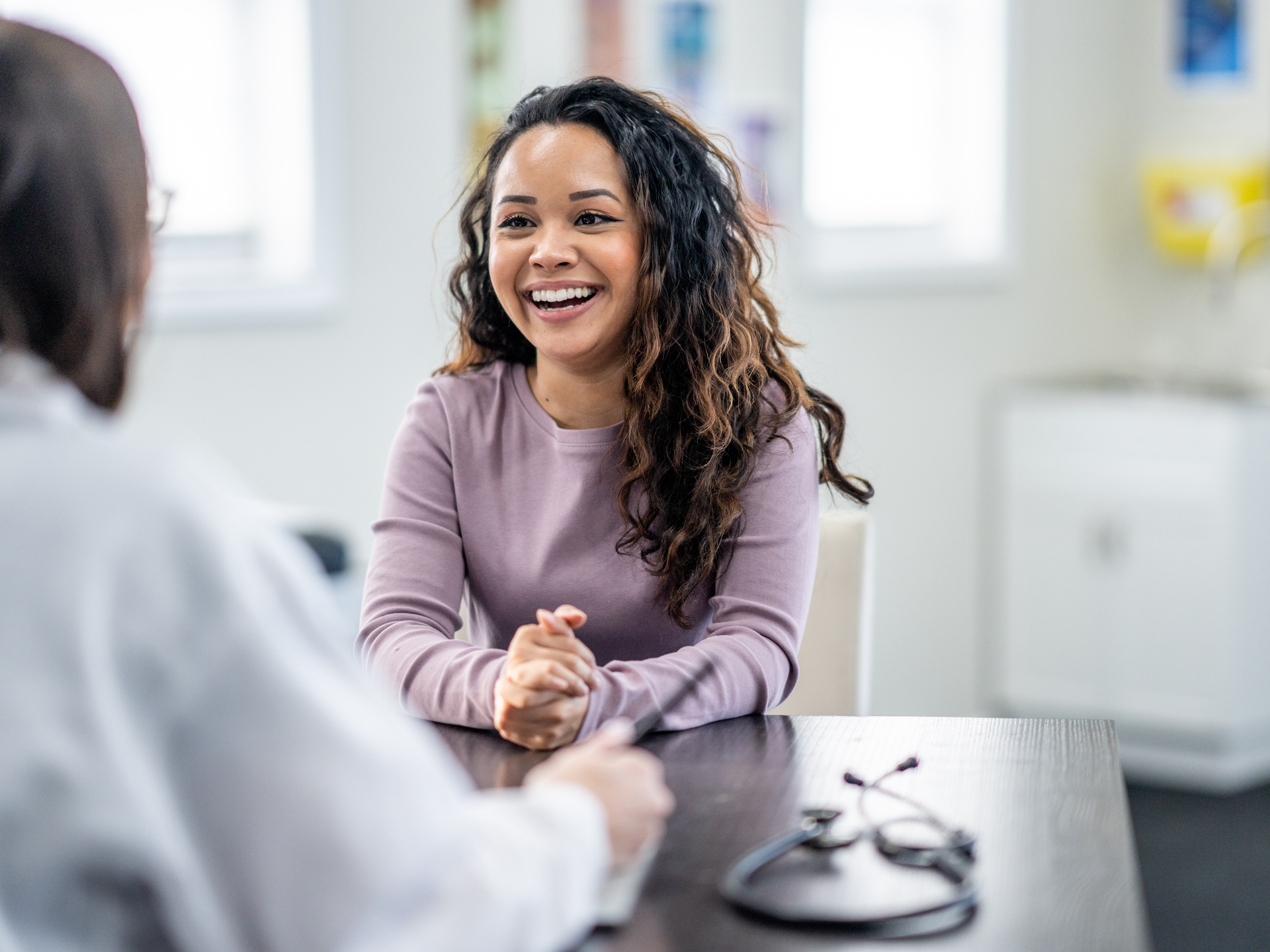 Young woman of mixed race, sits with female doctor discussing health concerns