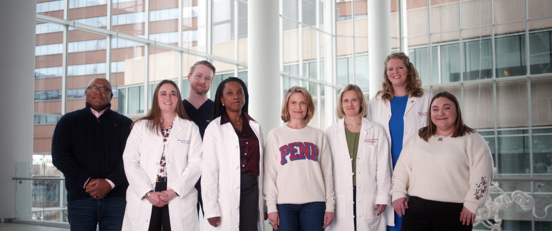 A group photo including Kate Korson in the center wearing a Penn sweatshirt, surrounded by people involved with her cancer care