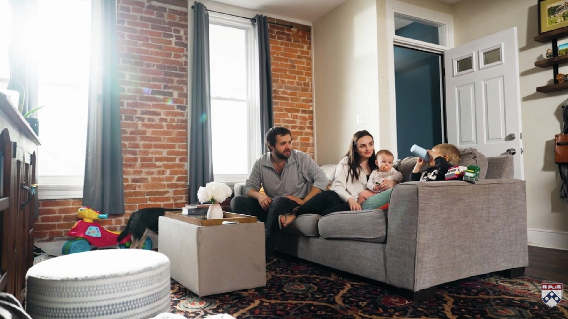 The Witmer family, including two parents and two small children, sit on the couch in their living room