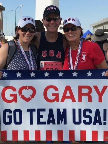 Heart transplant recipient Gary Rosenbaum after running a race, pictured with his family, holding a sign that says Go Gary, Go Team USA