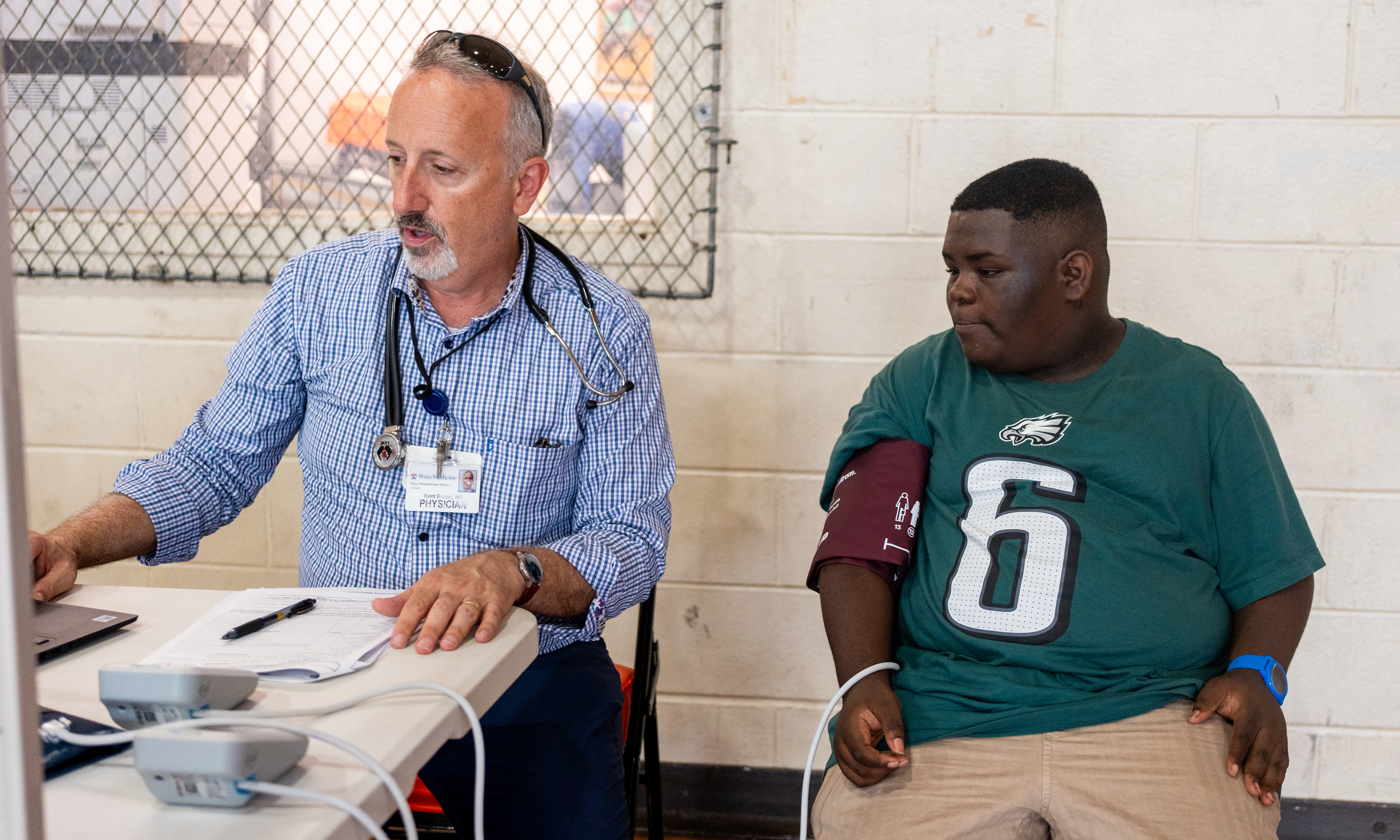 Kent Bream checking student Jaisen Smith’s blood pressure in a school gym