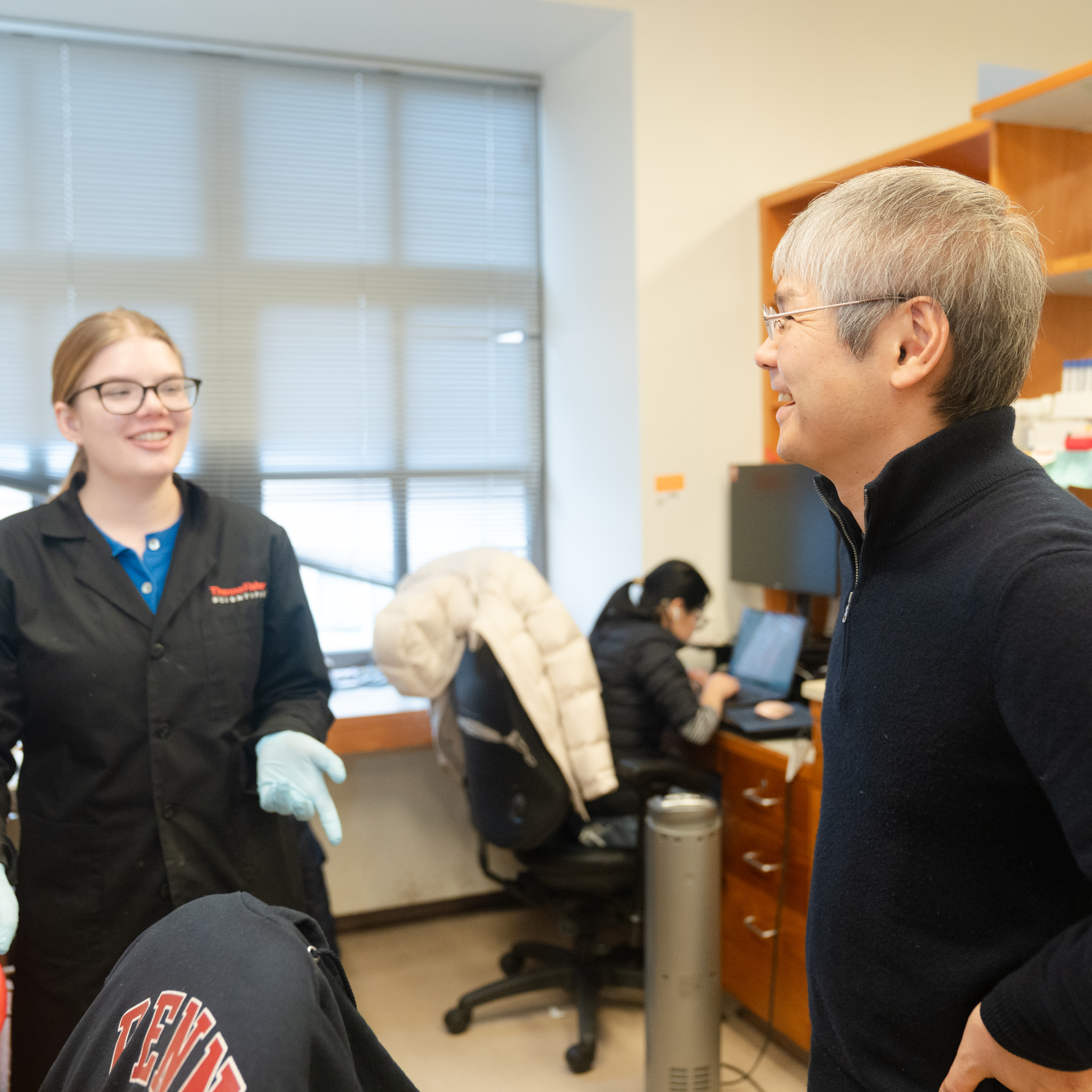 Kenji Murakami smiles while taking to a female scientist in his lab