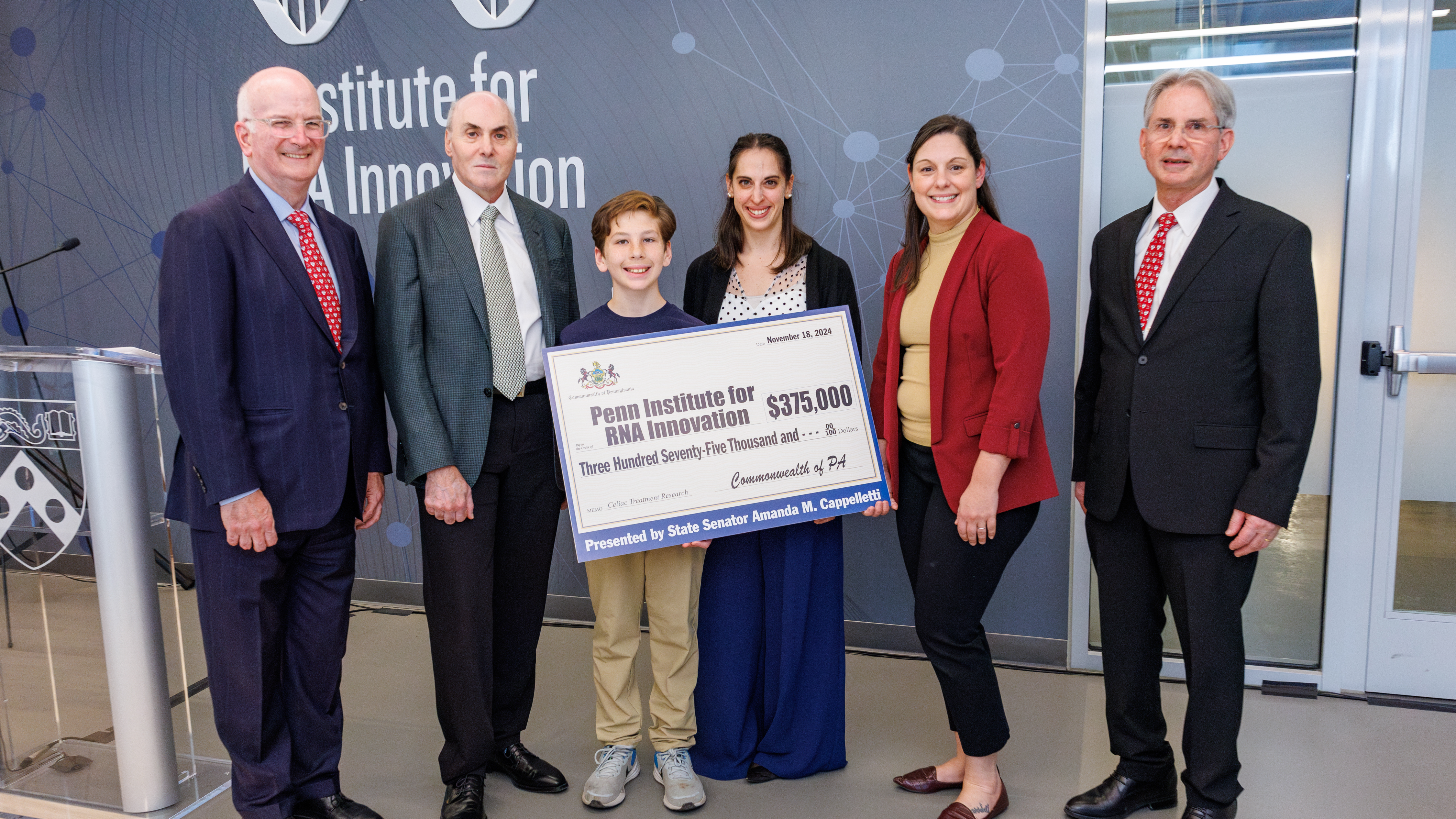 Jax Bari, Jilian Melamed, and other officials stand with an oversized check