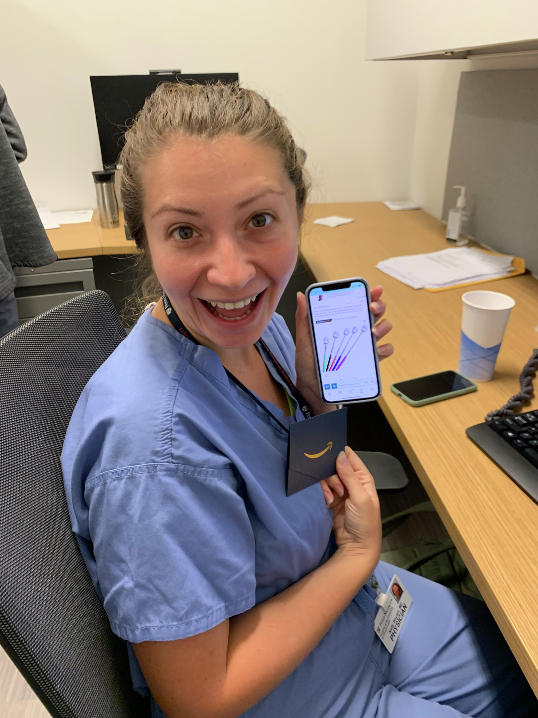 Kelly Boylan, MD, holding an amazon gift card next to a phone open to a listing of a back scratcher.jpg
