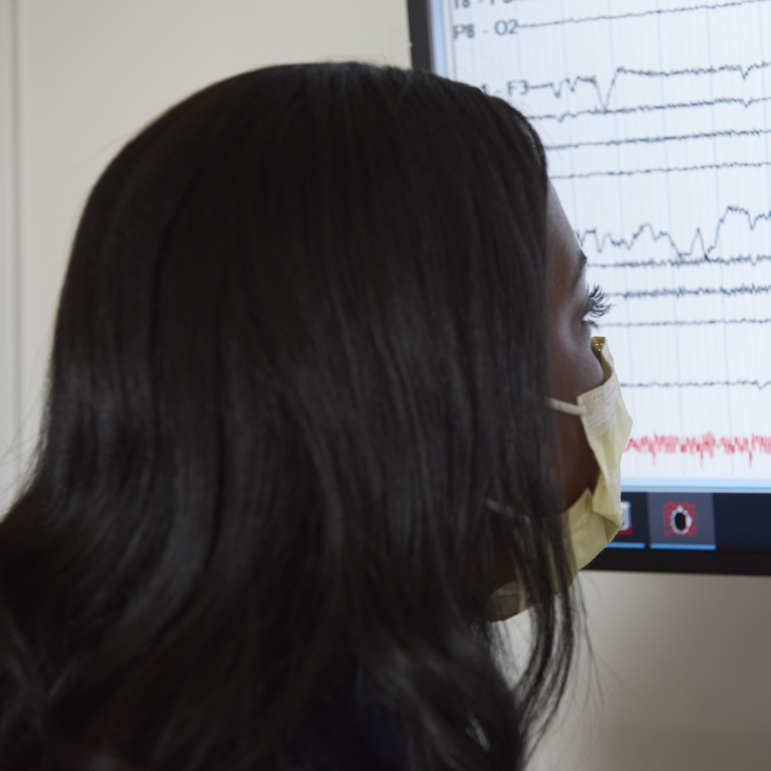 A nurse looks at brain data readouts on a screen