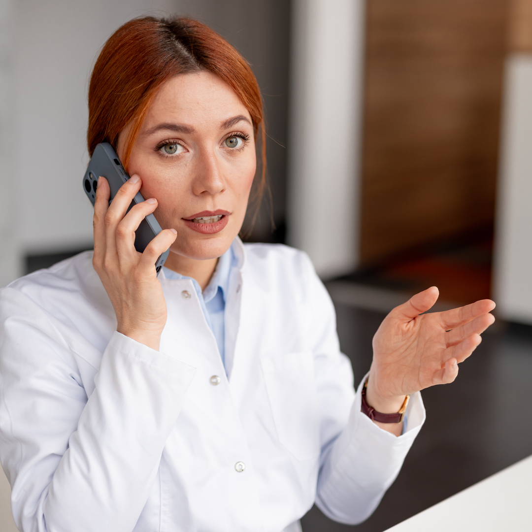 Medical professional in a white coat speaking on the phone, expressing communication and attentiveness in a professional office environment.