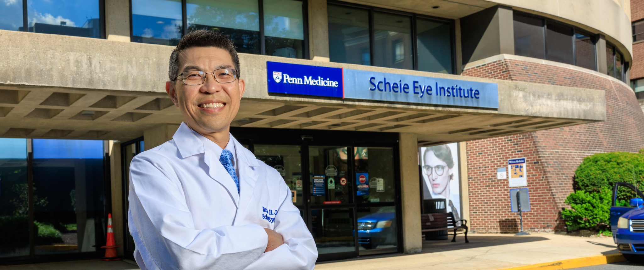 Bennie Jeng, smiling, standing outside of the Scheie Eye Institute