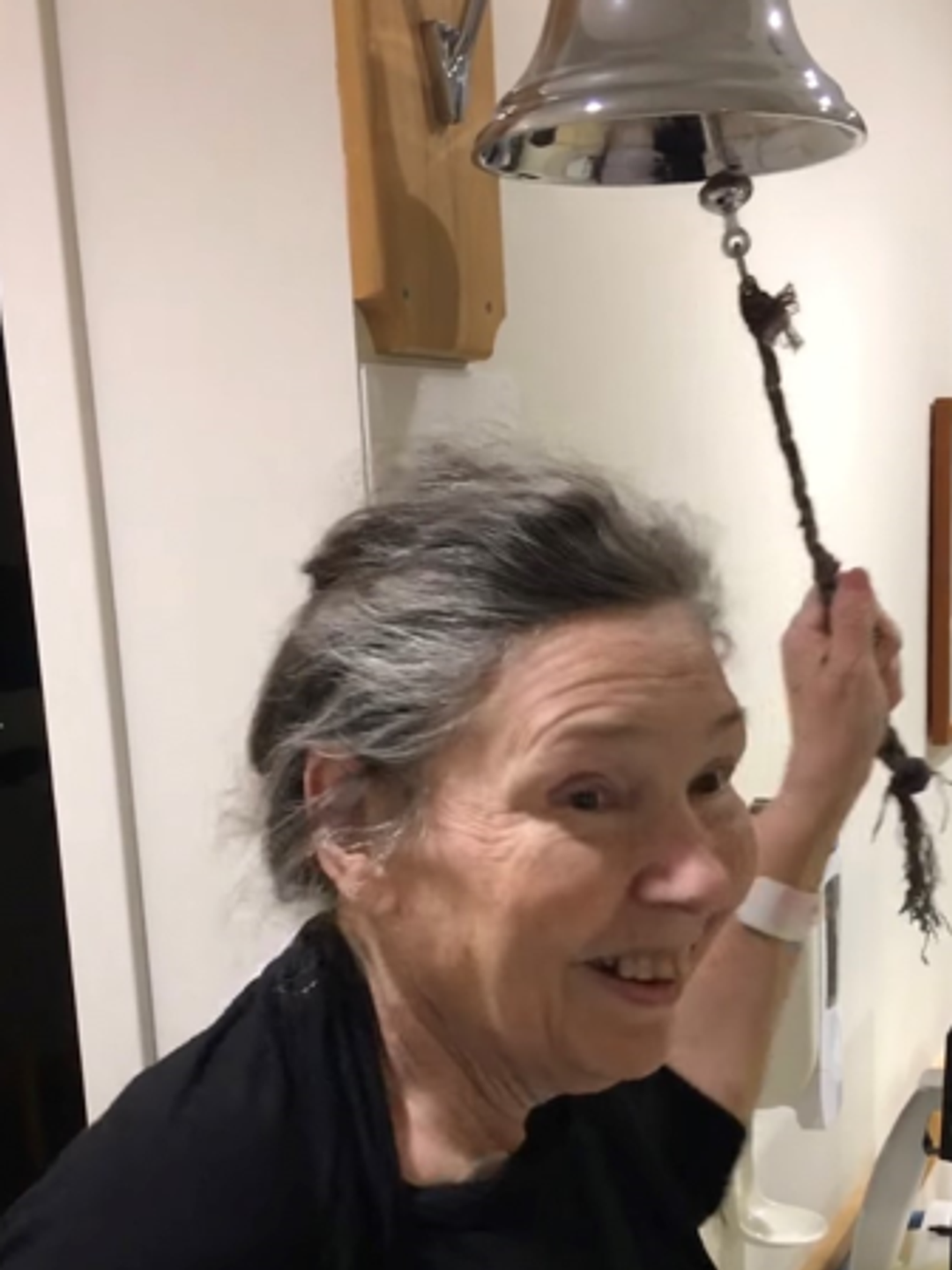 Cynthia Olds smiling as she rings the large silver Cancer Bell