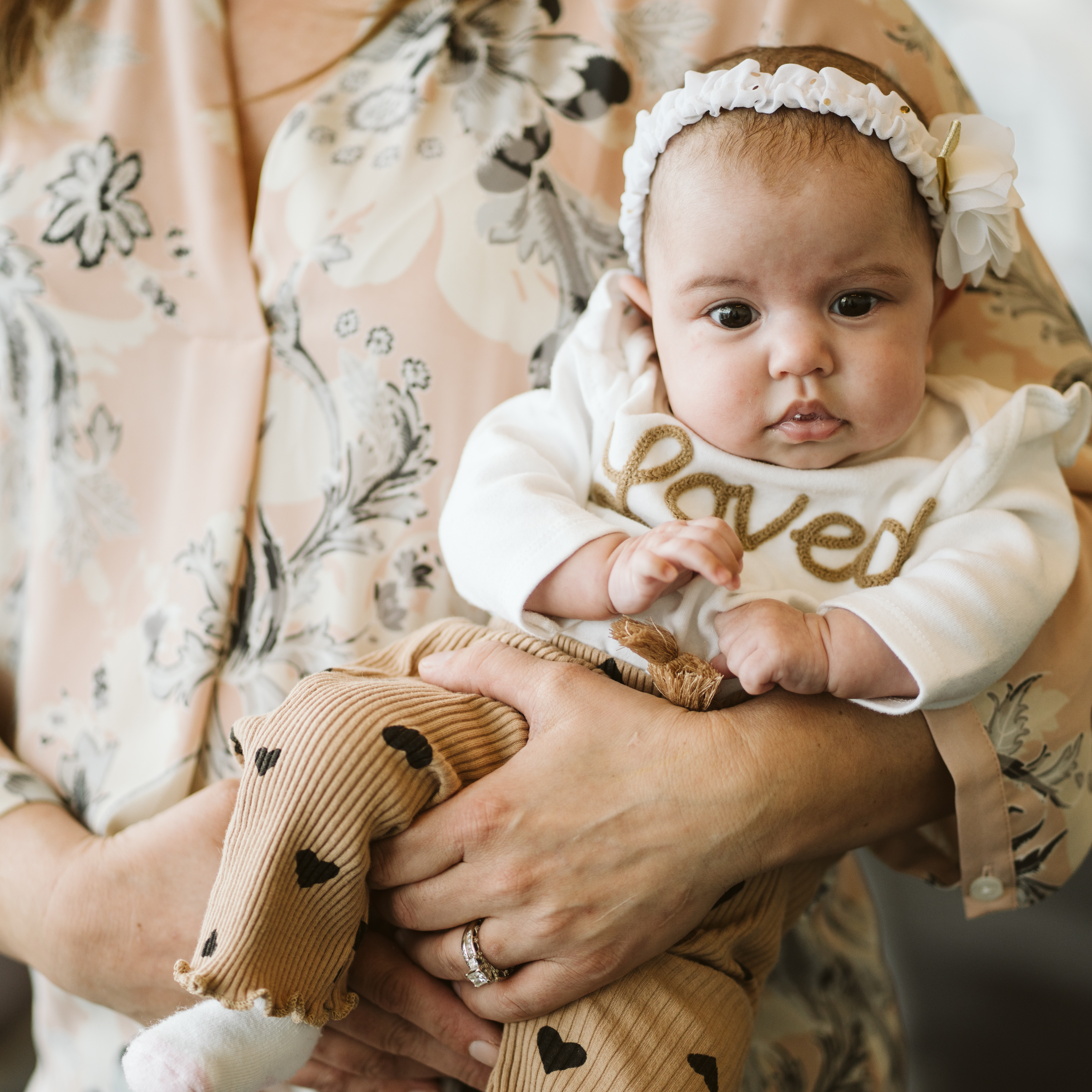 Baby Adrianna being held while wearing a shirt that says "Loved"