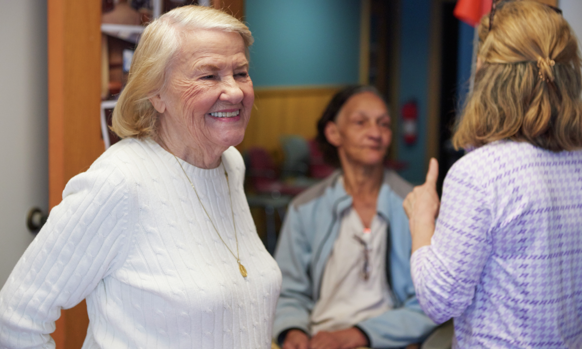 An older woman in a white sweater smiles broadly
