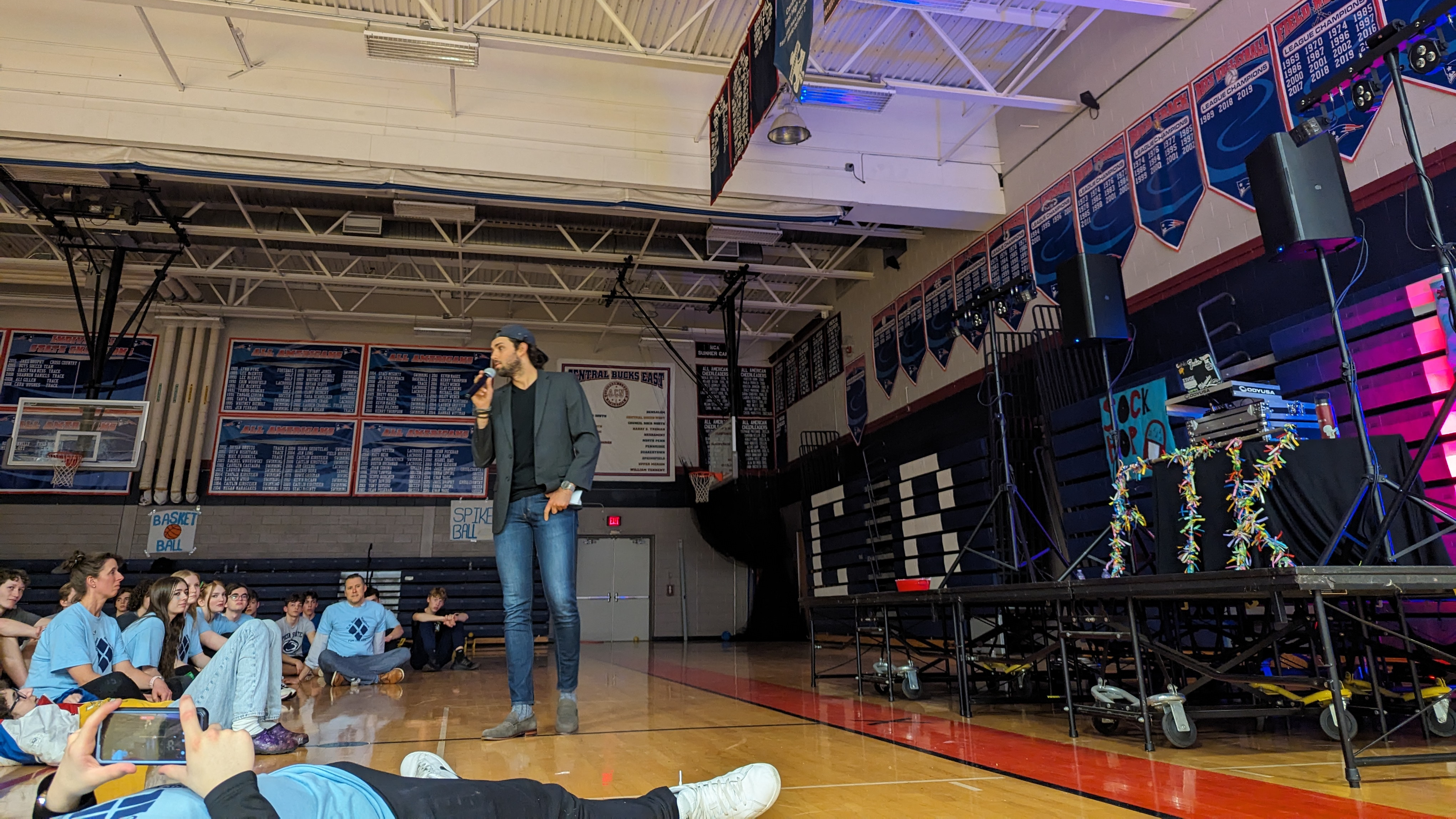 Chris Baccash speaks to a crowd of kids gathered in a school gym