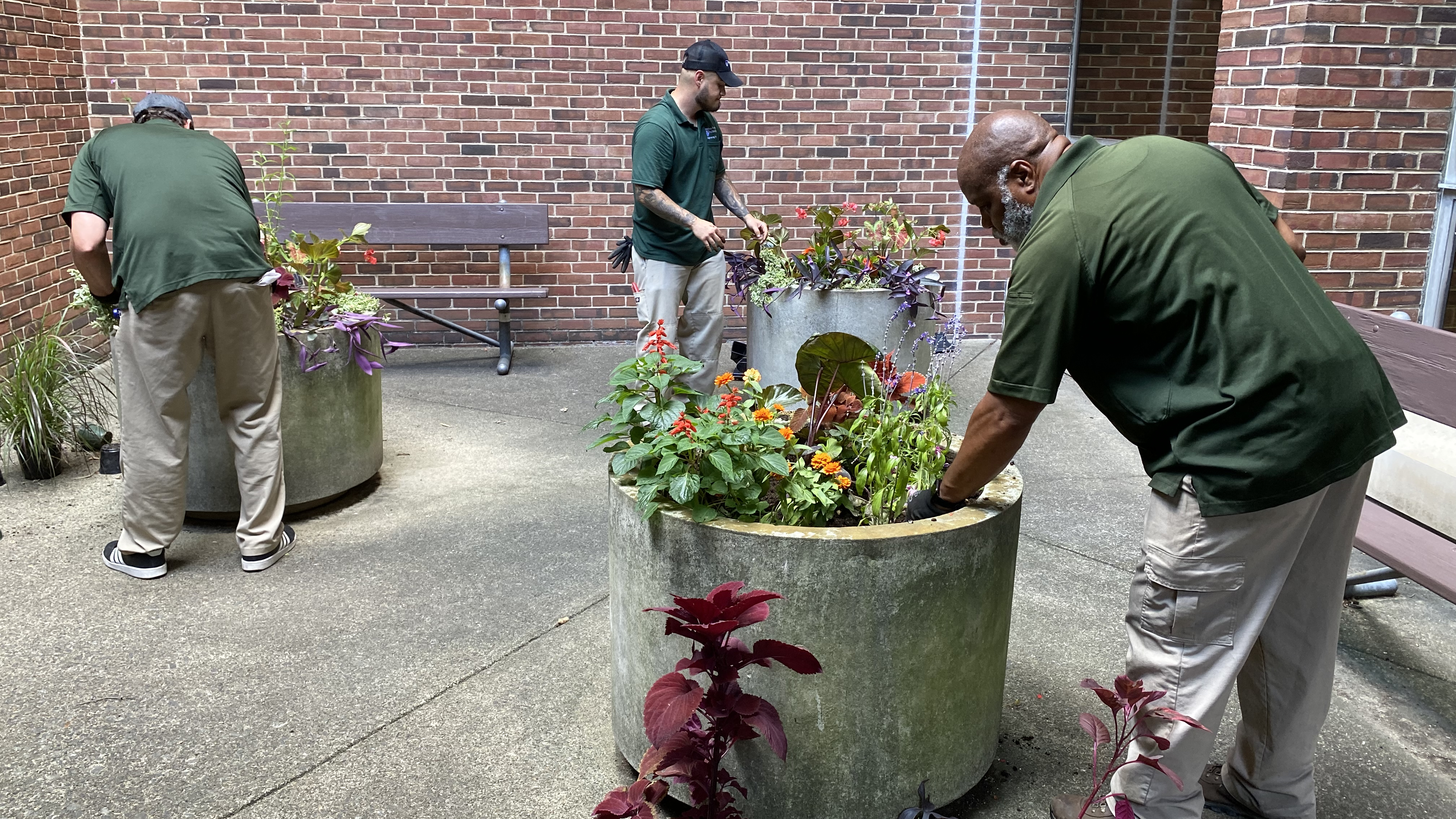 Earl Johnson, Blake Sieminski, and Nick Sambucetti prepare three planters with a variety of flowers outside of Pennsylvania Hospital