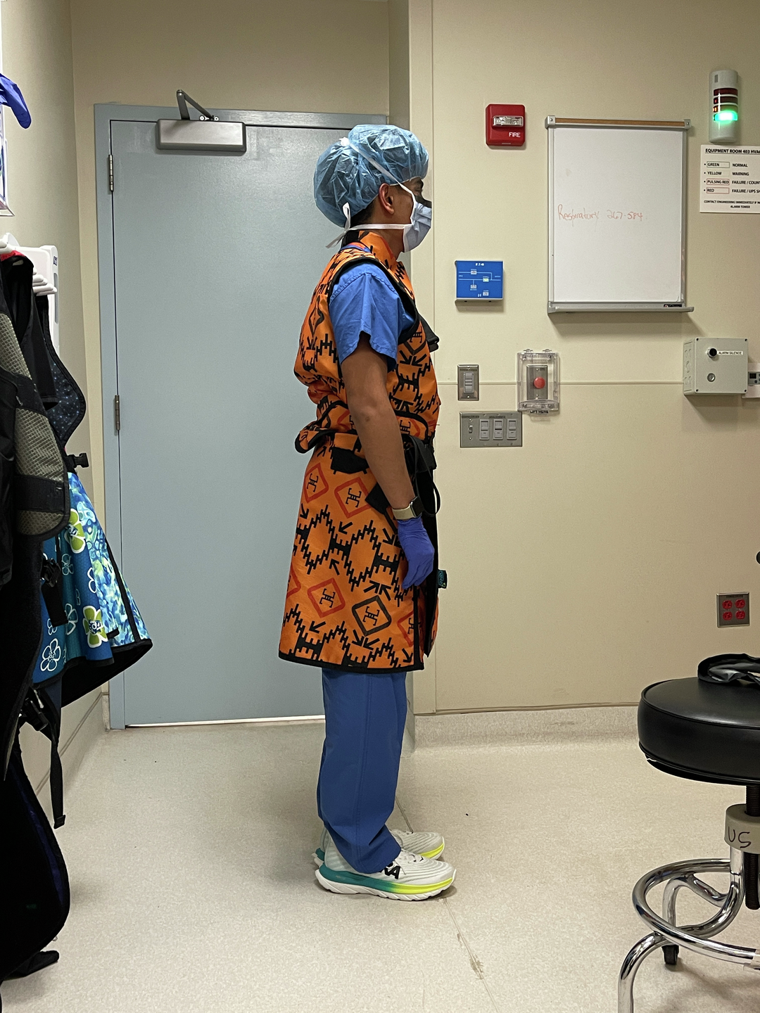 A full-body photo of Greyson Graham fully covered in scrubs, bonnet, mask, and a protective apron
