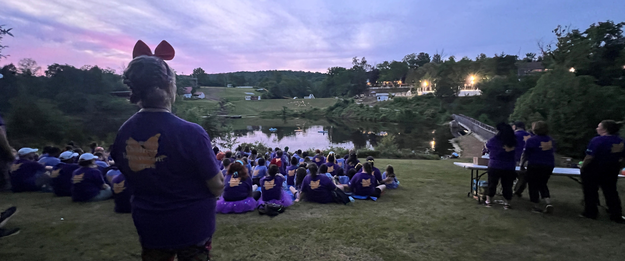 Campers sit on a hill above a lake before the Luminary Ceremony at Camp Erin
